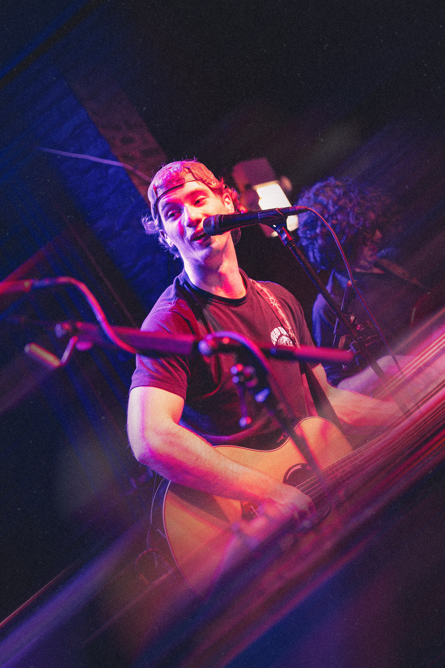DJ performing at a nightclub with colorful purple and pink lighting creating an energetic atmosphere during a live set.