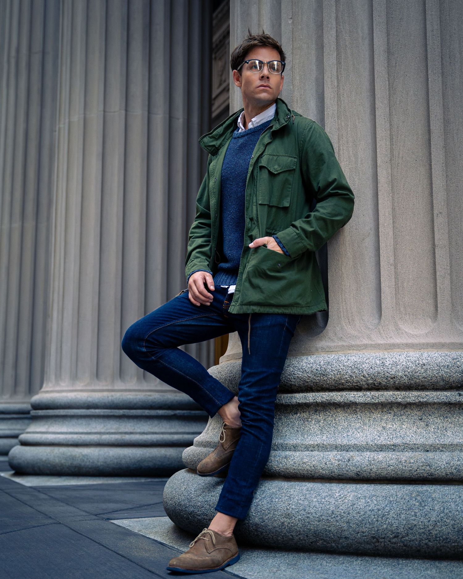 Urban fashion photography showcasing green jacket and blue sweater against classical architecture.