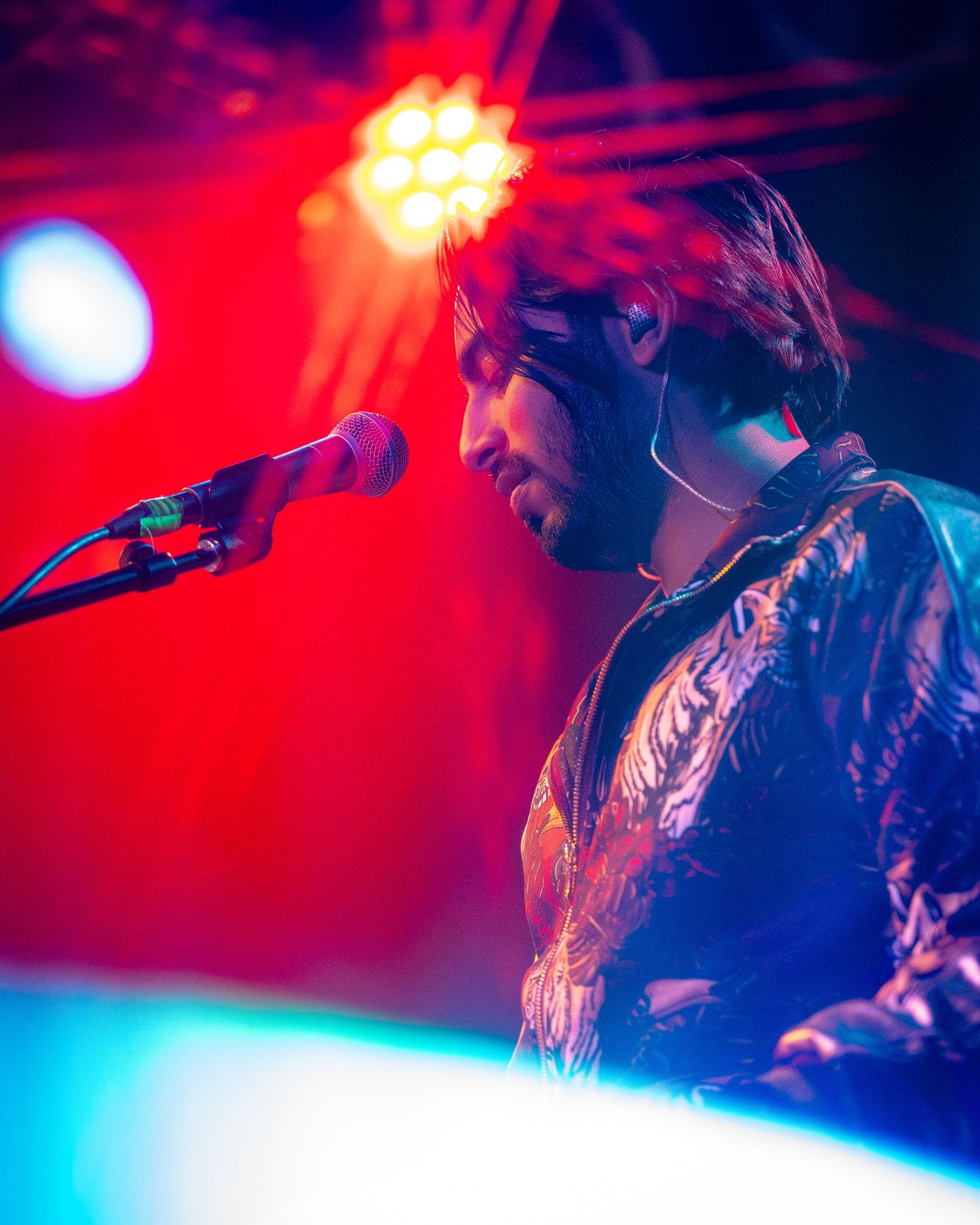 Musician performs under intense red and blue stage lighting effects.