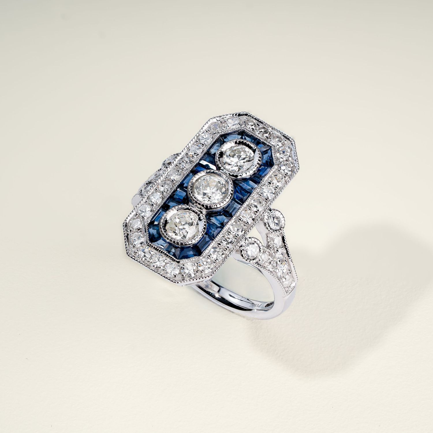 Vintage-style white gold ring with sapphire accents and diamond pavé detailing.