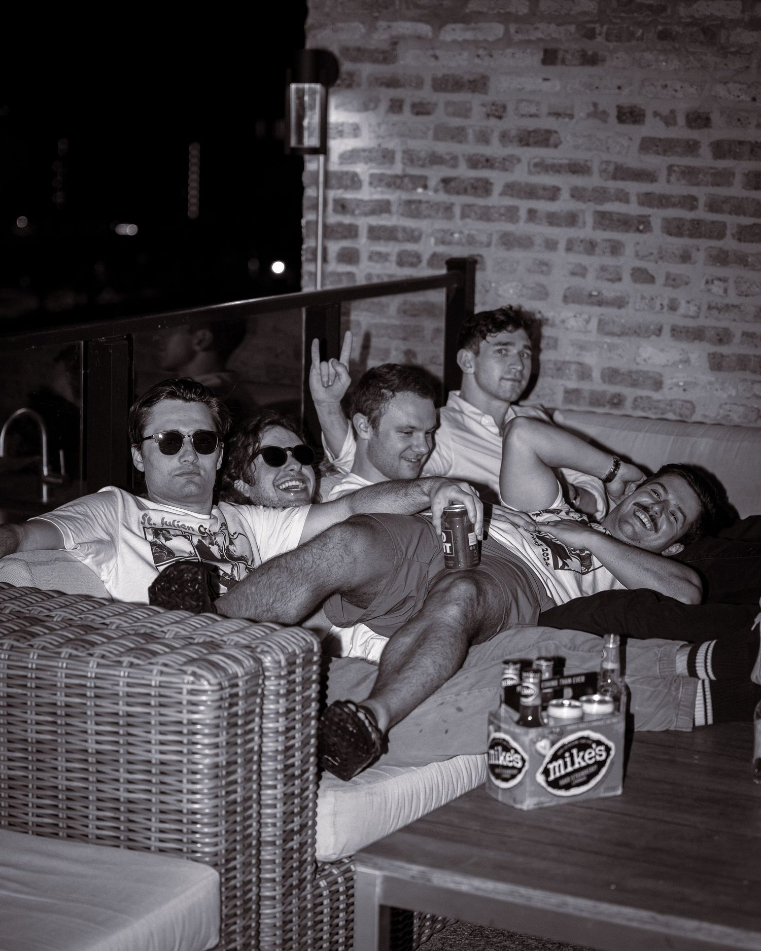Group relaxing on outdoor furniture with drinks in black and white photography.