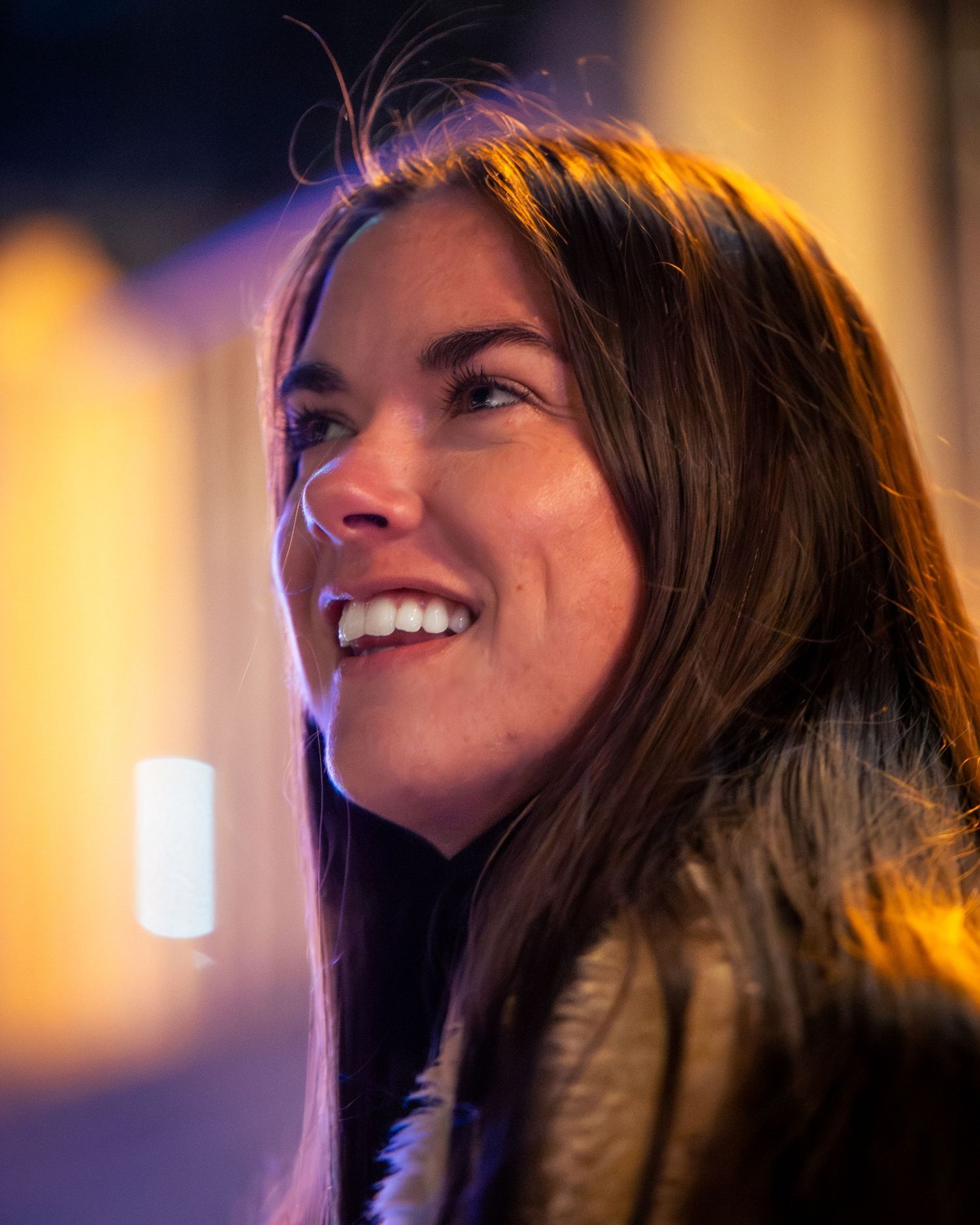 Candid nighttime portrait with warm lighting capturing joyful expression.