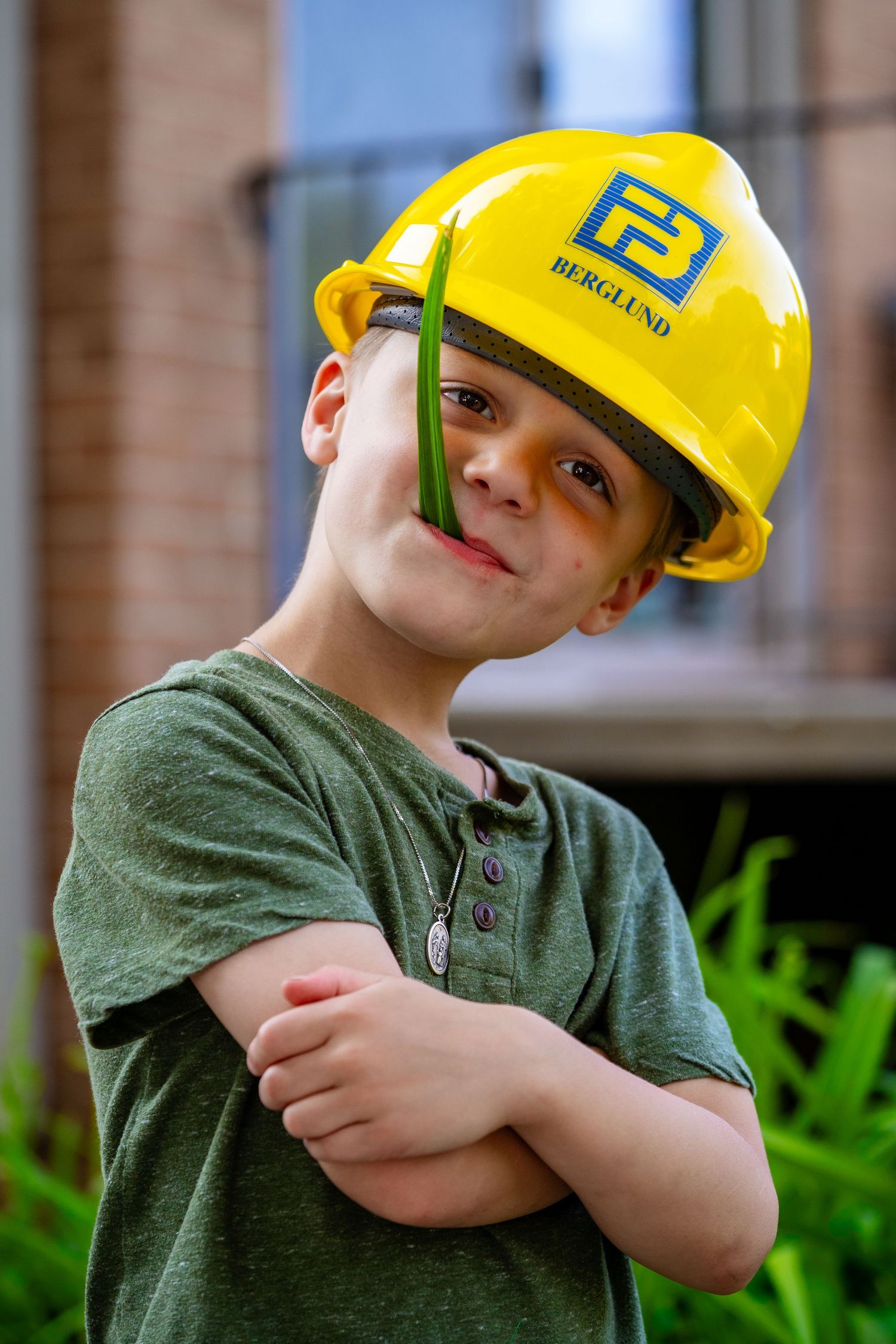 Young child wearing a yellow hard hat and green shirt making silly faces in a series of photos.