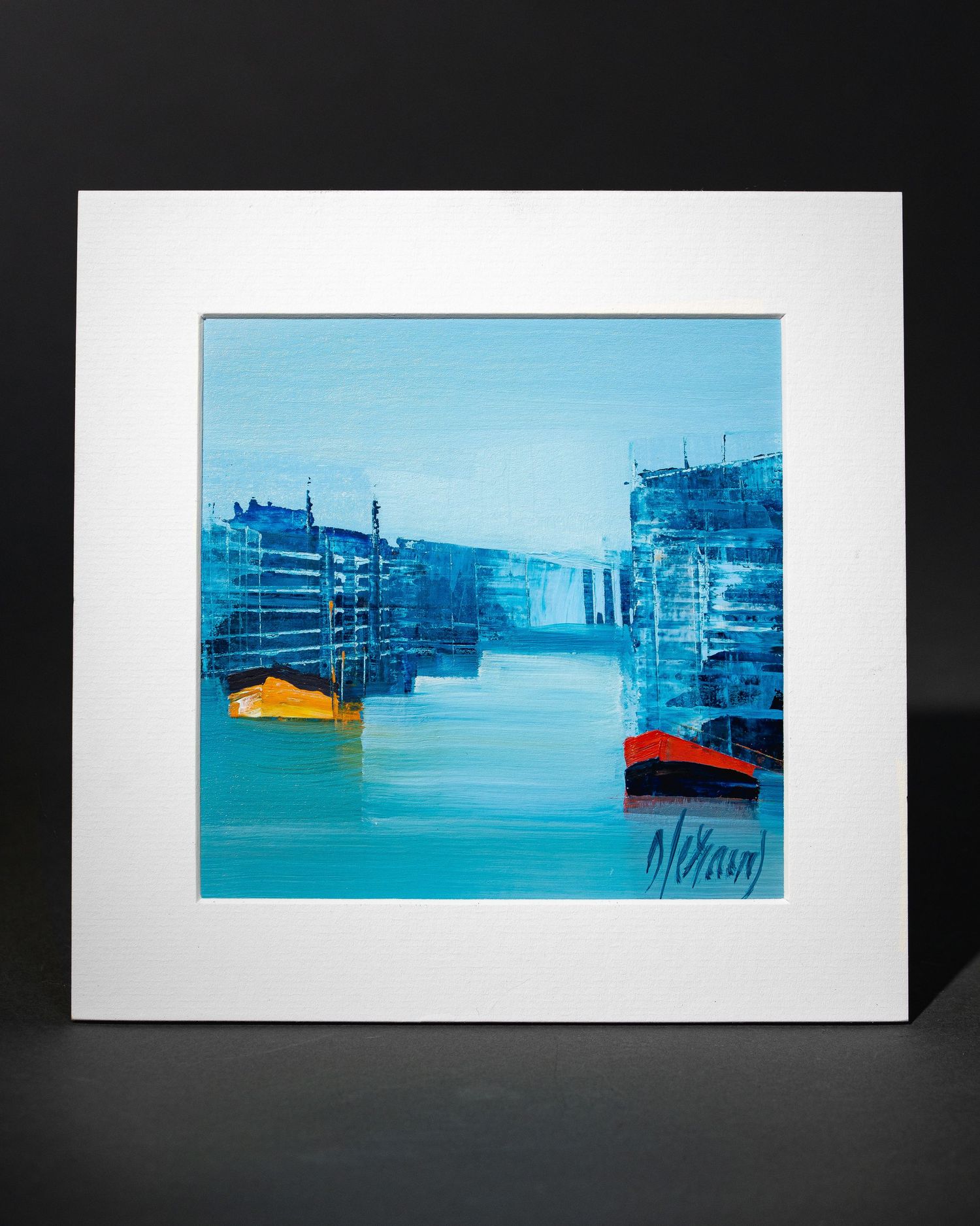 Abstract watercolor paintings of boats in a harbor with blue tones displayed in gallery-style frames on a dark wall.