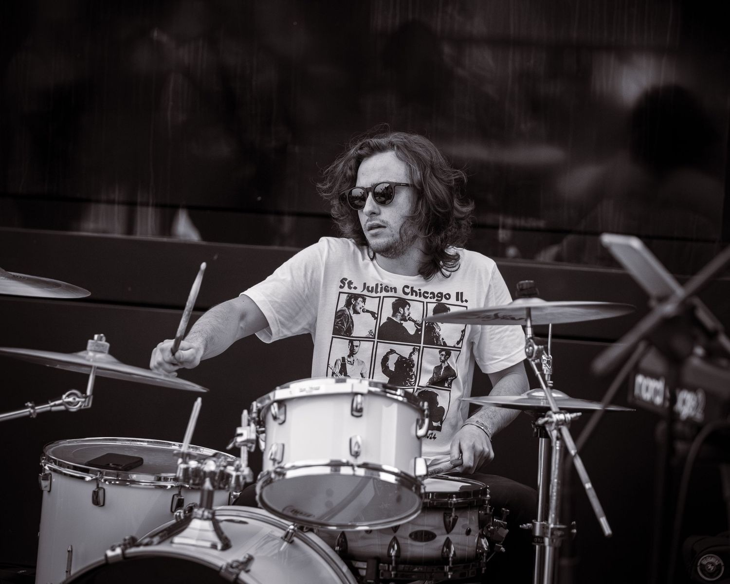 Drummer performing on stage wearing graphic t-shirt in black and white photo.