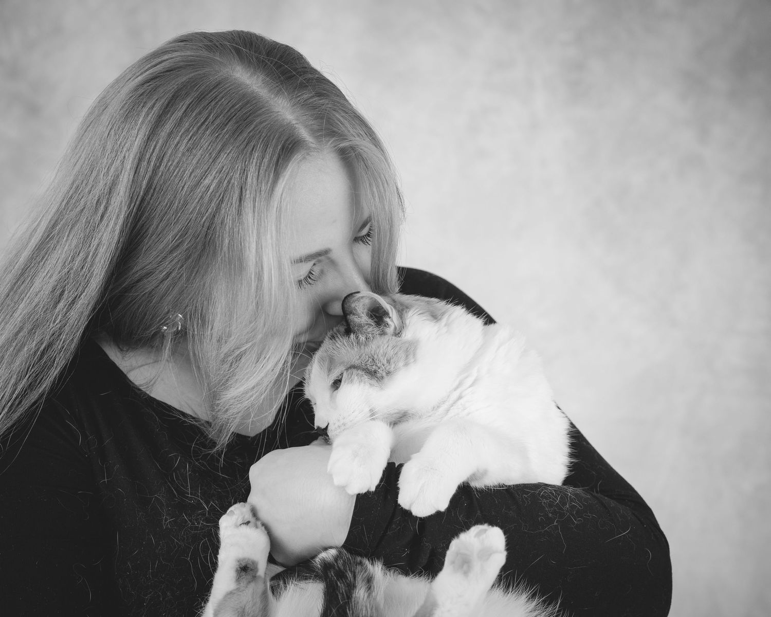 Black and white photo series showing a person affectionately nuzzling with a white cat in five tender moments.