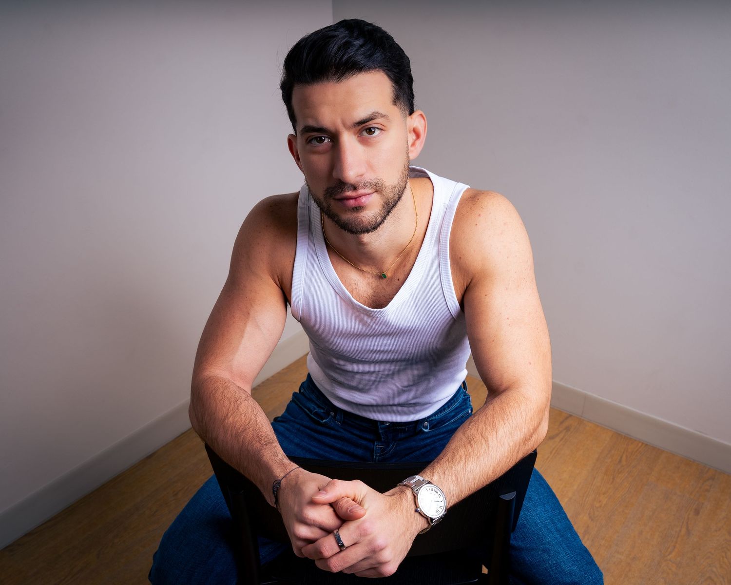 Studio portrait series in white tank top and jeans against neutral background.