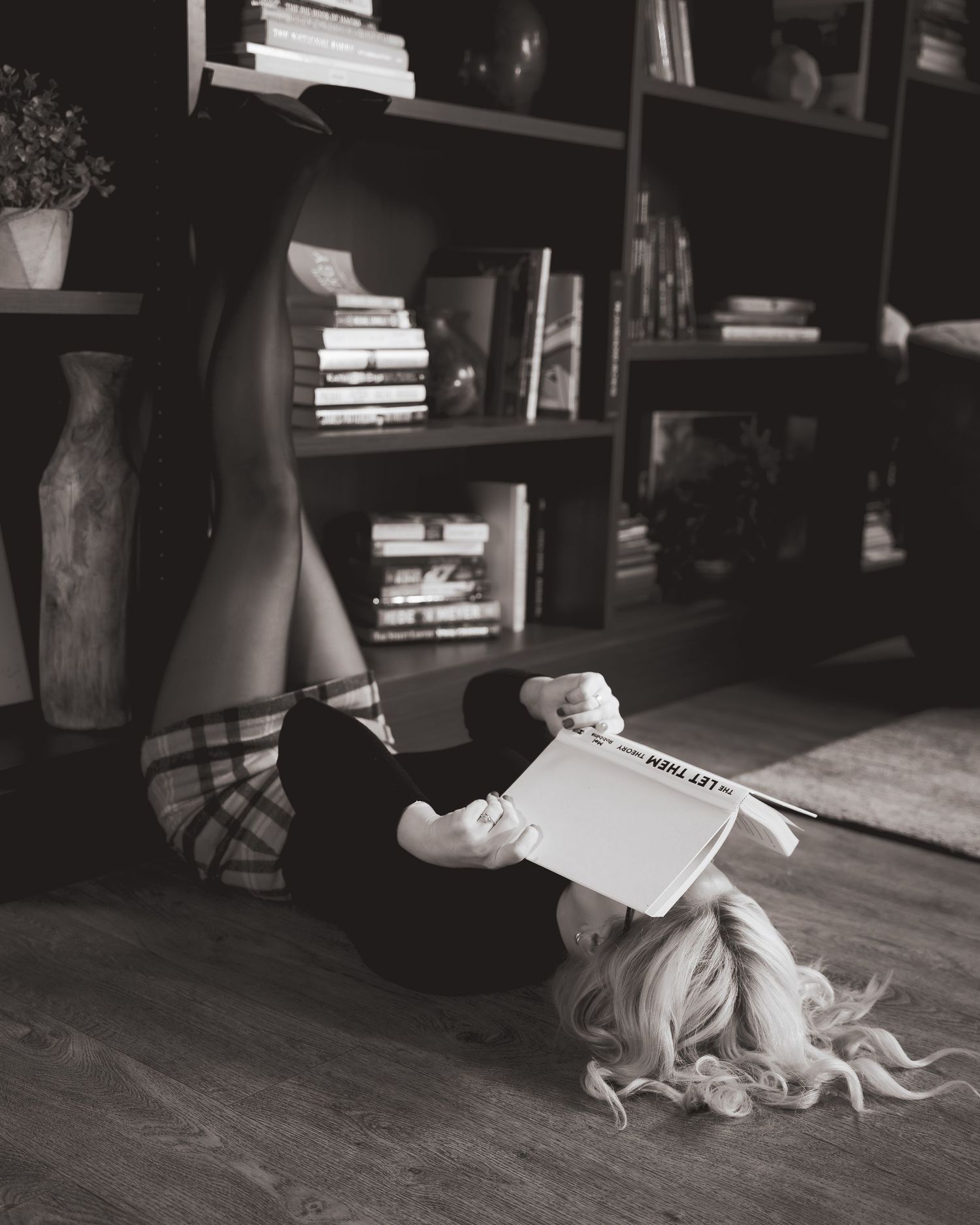 A series of black and white photos showing a person lying on the floor with books in a library or study.