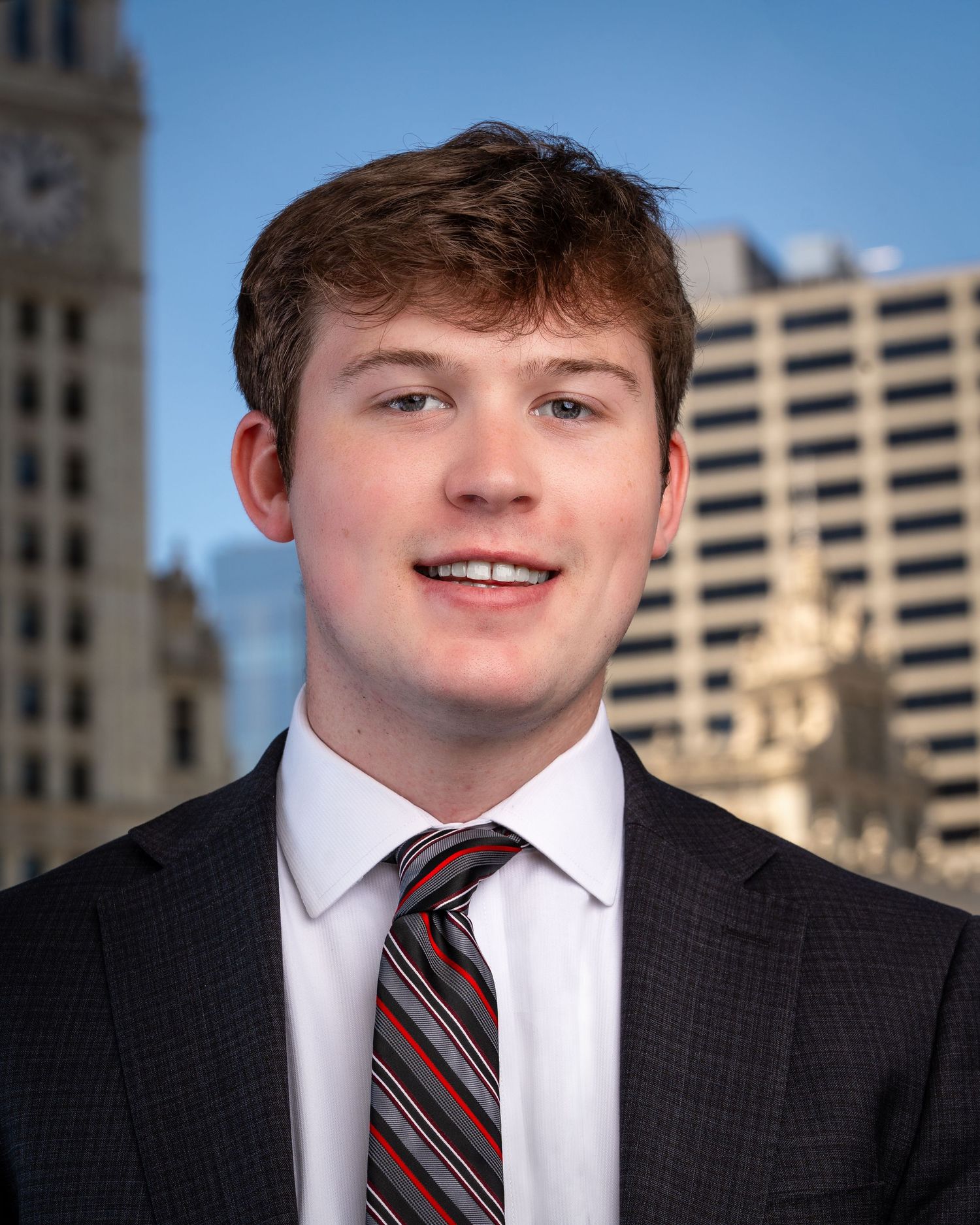 Professional portrait series with dark suit and striped tie against city architecture.