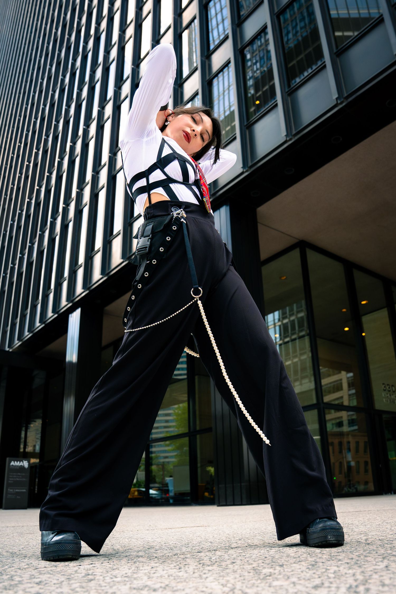 Dynamic urban fashion pose against a modern glass building facade.