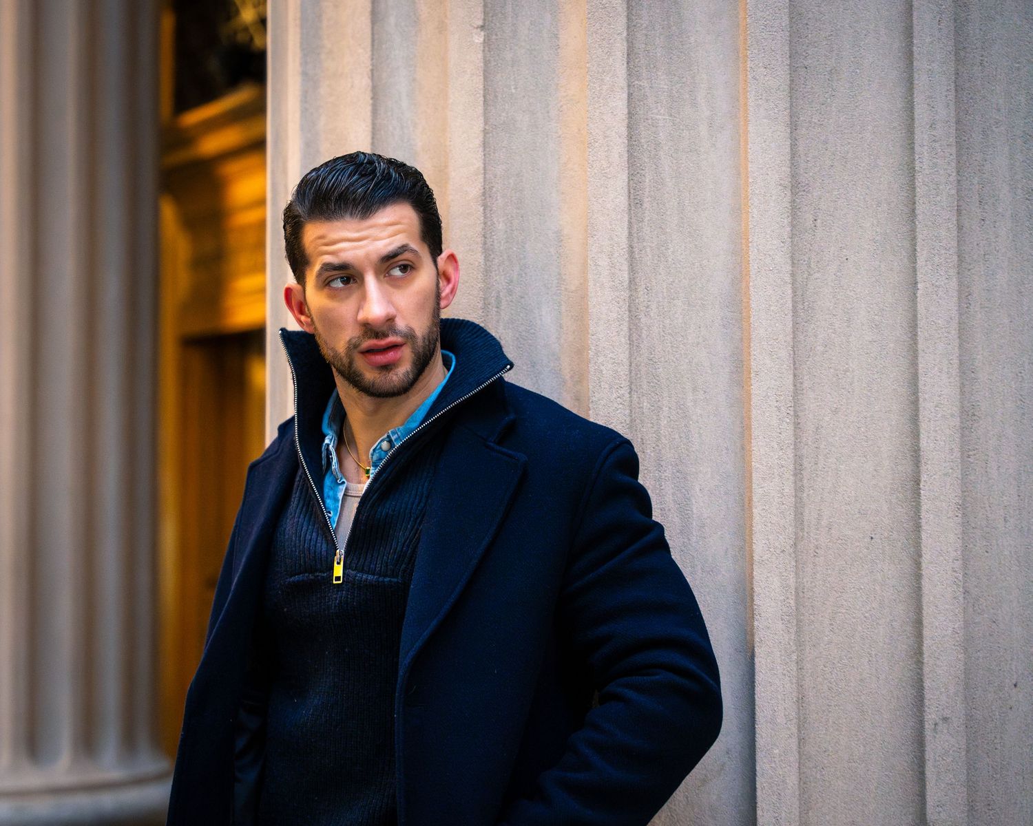 Urban fashion photo series with person in navy coat against architectural columns.