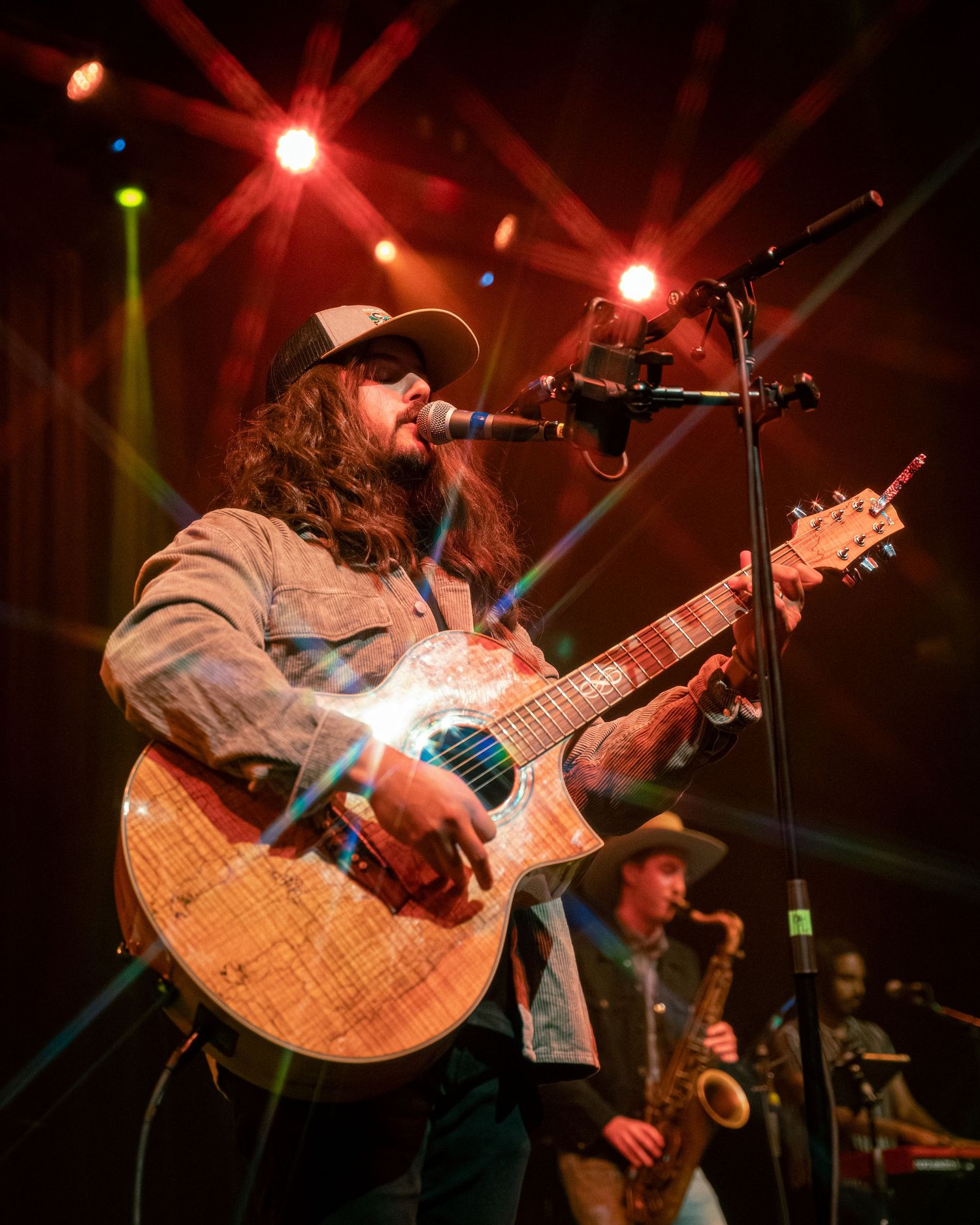 Musicians performing on stage with dramatic red and green lighting effects.