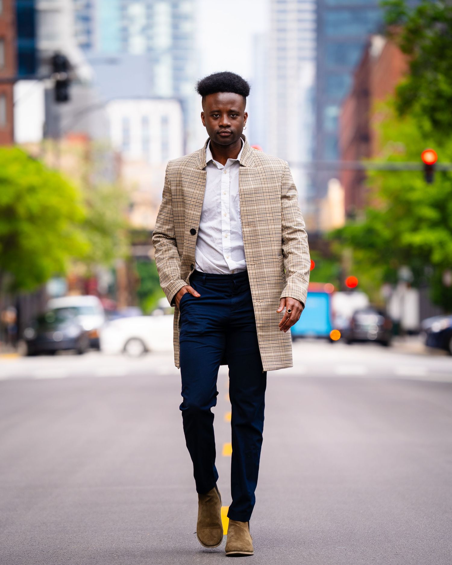 Person wearing plaid blazer and navy pants walking on city street.