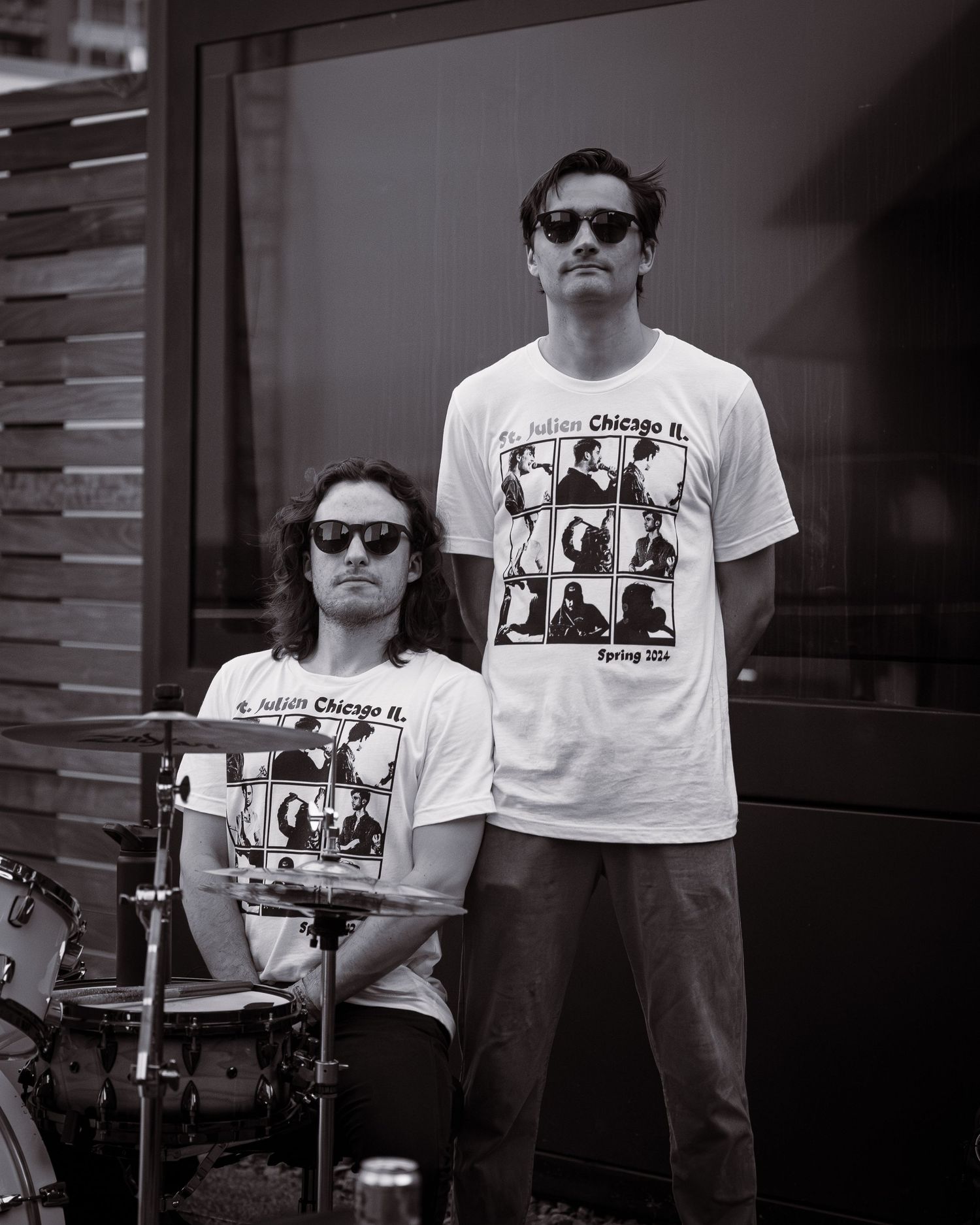 Two band members in matching t-shirts pose with instruments in black and white.