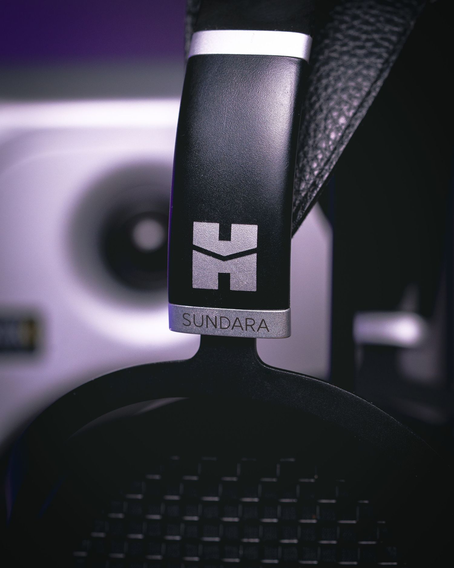 Close-up view of black gaming headset details showing textured surfaces and branding elements in dramatic lighting.