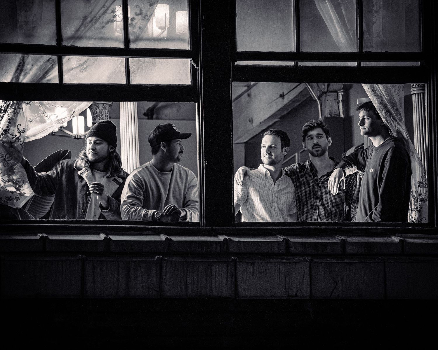 Black and white panoramic view of people through window frames.