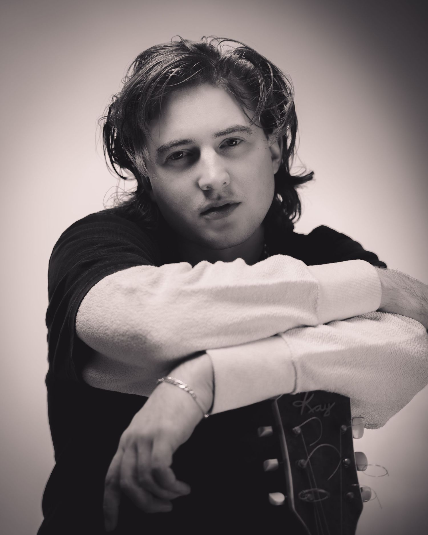 Black and white portrait series showing musician resting head on folded arms in dramatic lighting.