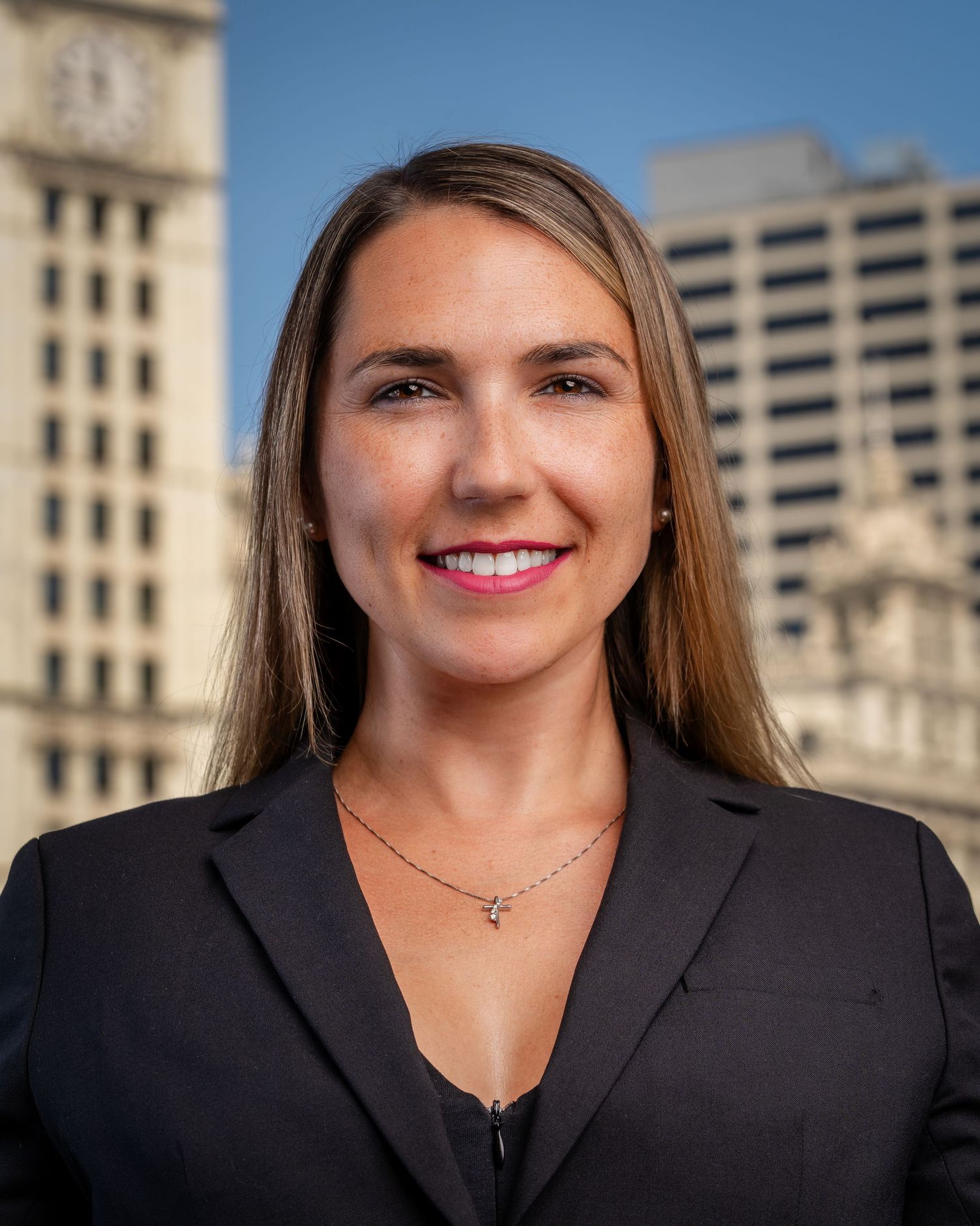 Business professional portraits with black blazer against modern building exterior.