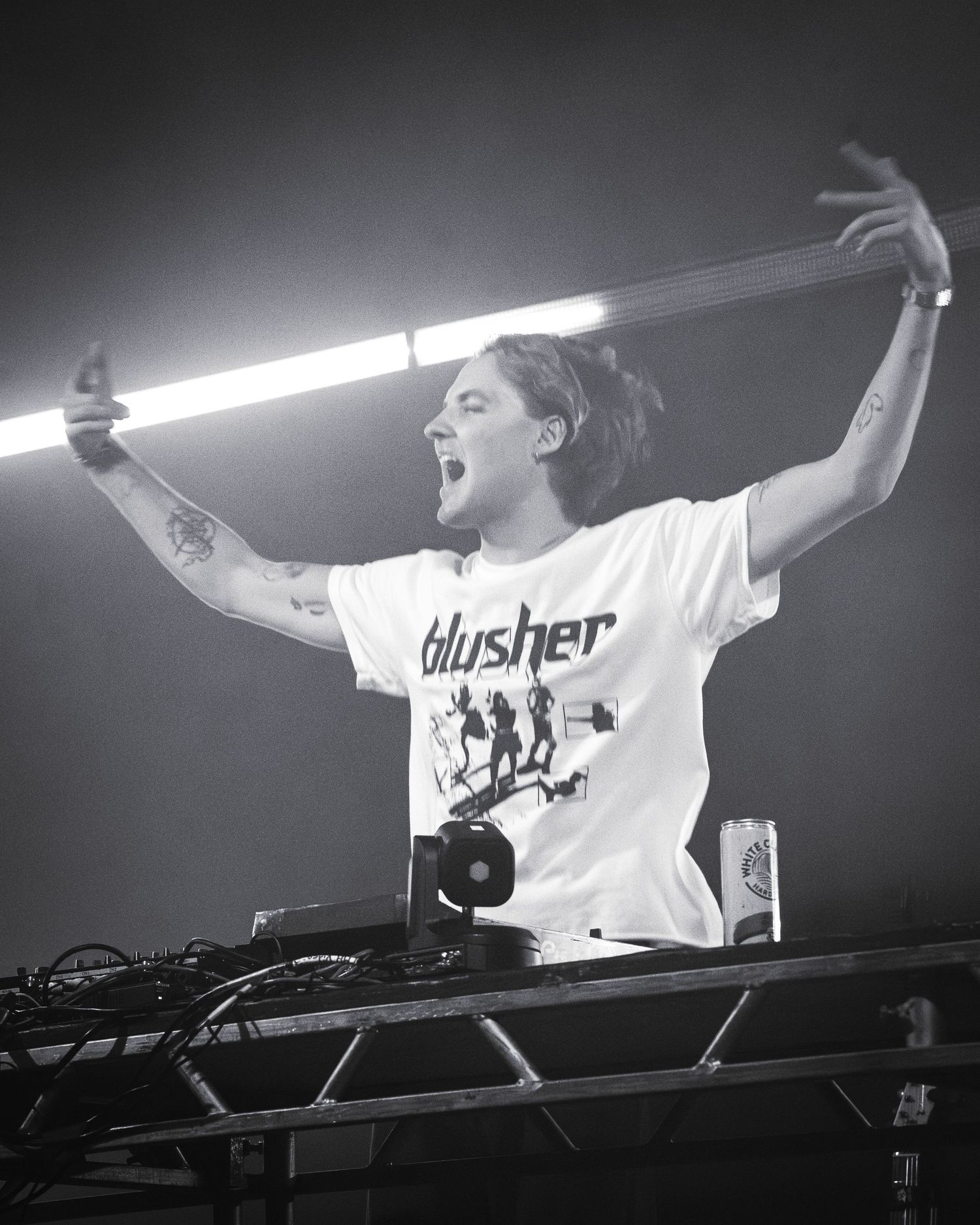 Energetic DJ performance with raised hands and lighting equipment on stage.
