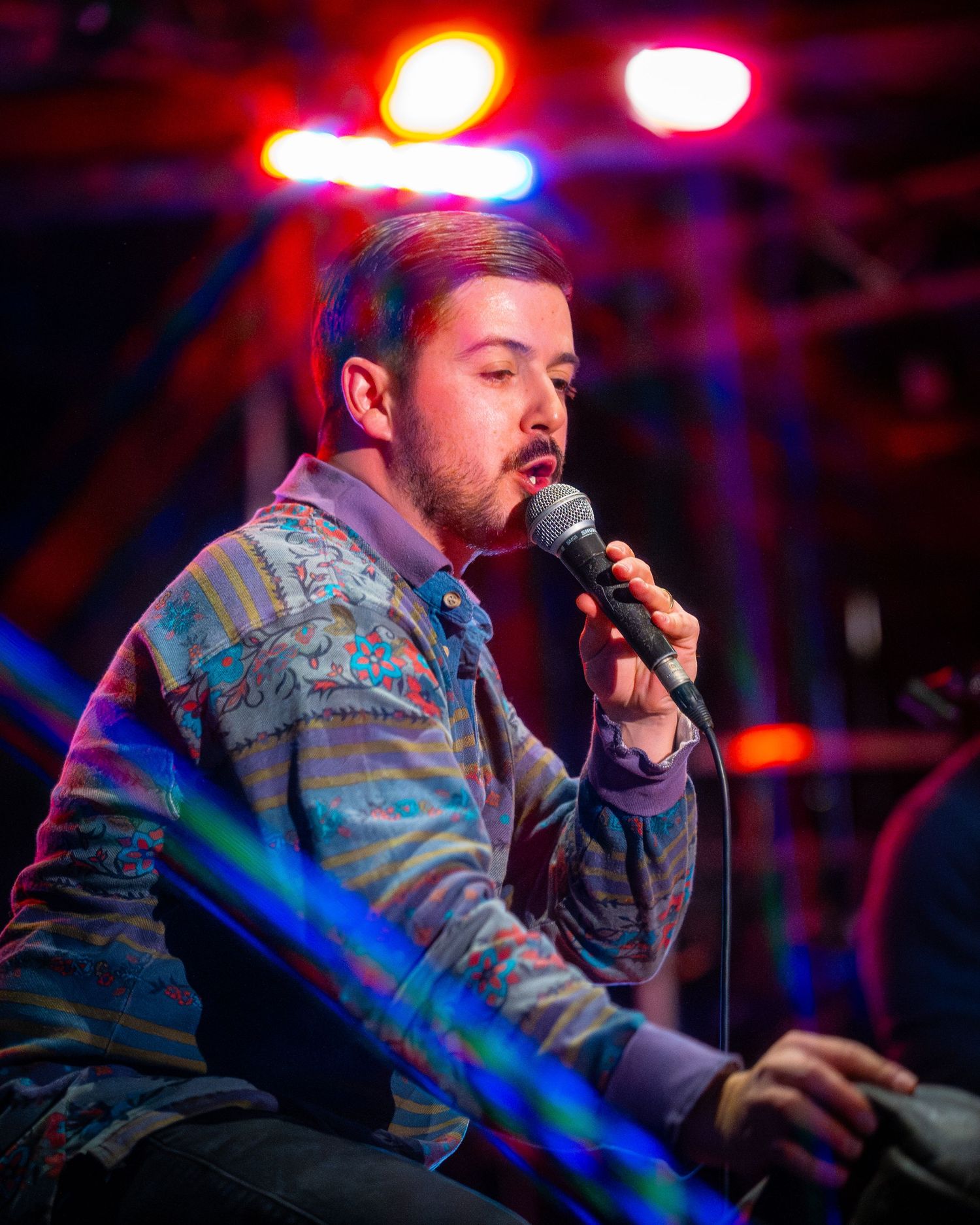 Close-up of concert performance under red and pink stage lighting.
