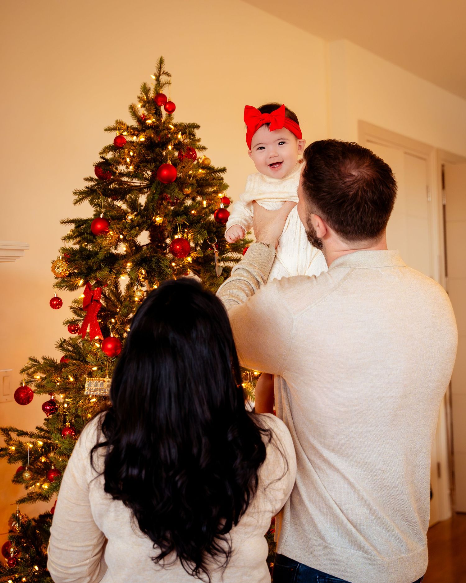A couple decorates a Christmas tree together in their home, placing ornaments and lights on the festive evergreen.