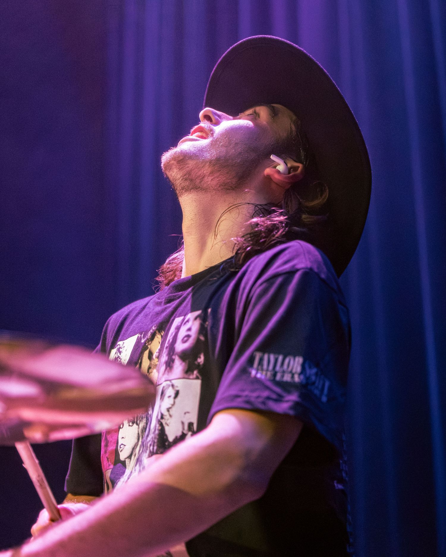 Performer passionately singing on stage with dramatic blue and purple lighting effects.