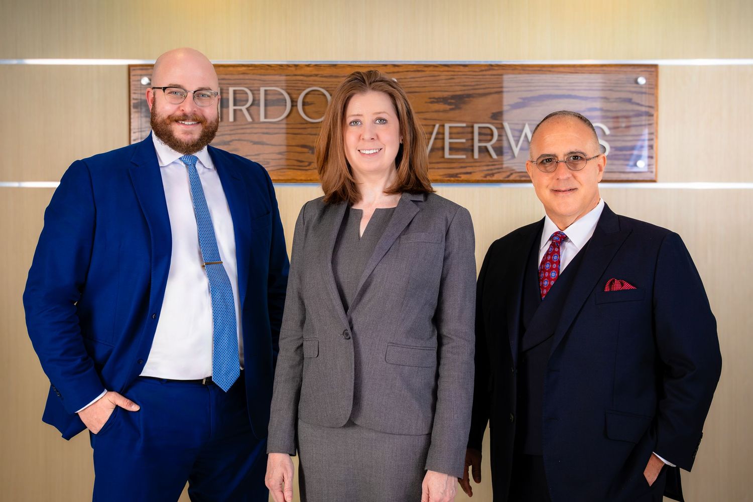 Law firm partners standing together in front of company signage.