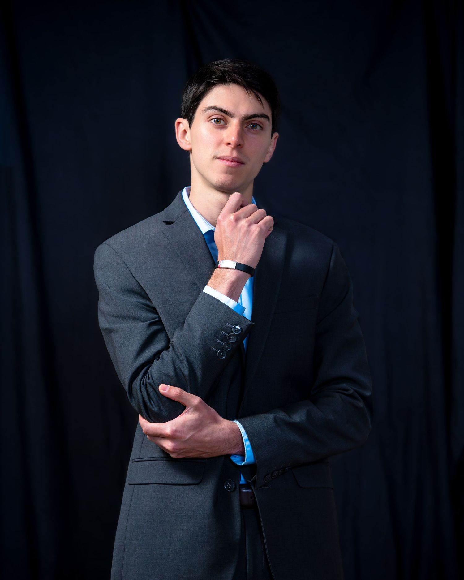 Portrait of a person in business attire posing thoughtfully against a dark background.