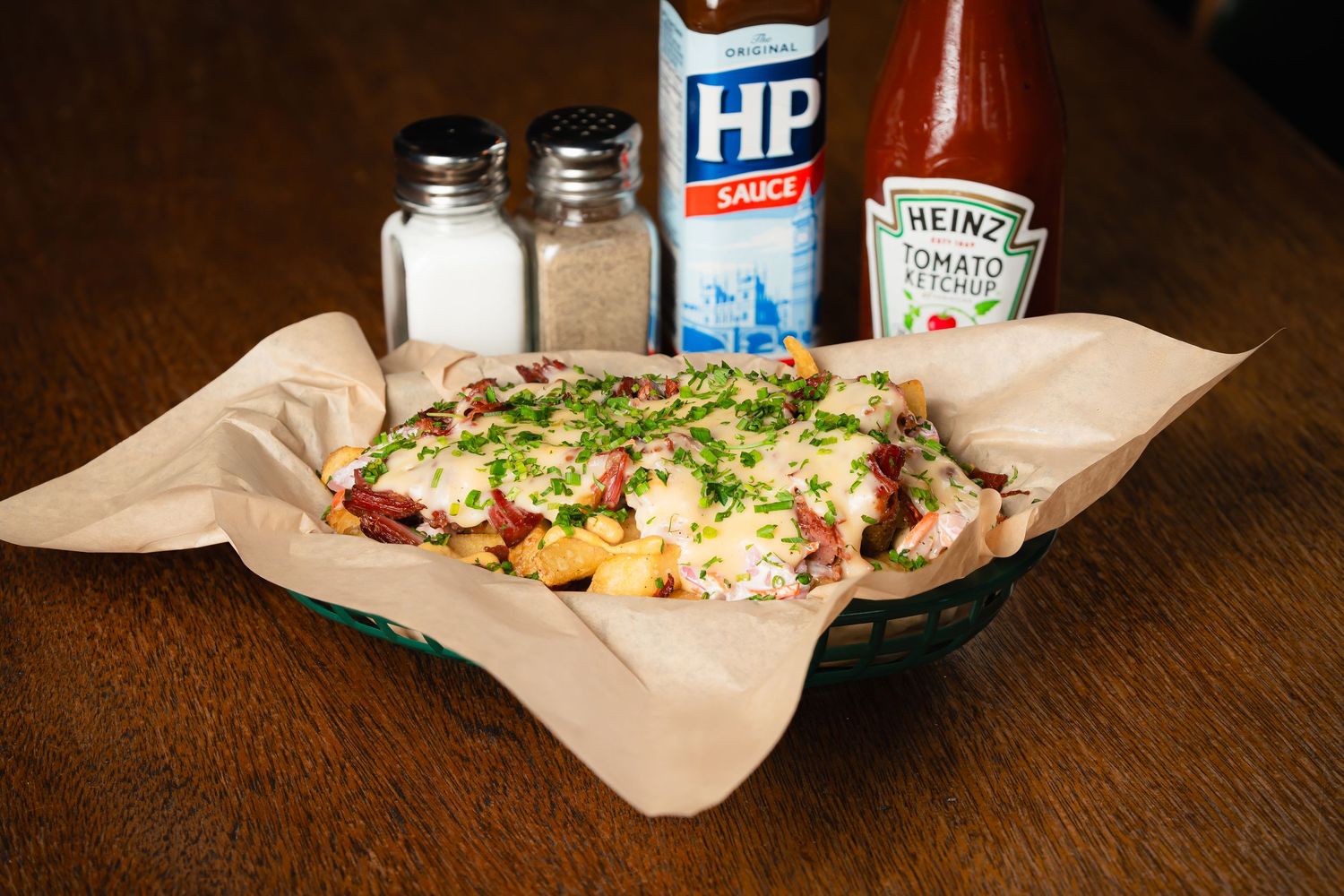 Loaded sandwich with fresh toppings served with condiments on brown paper.