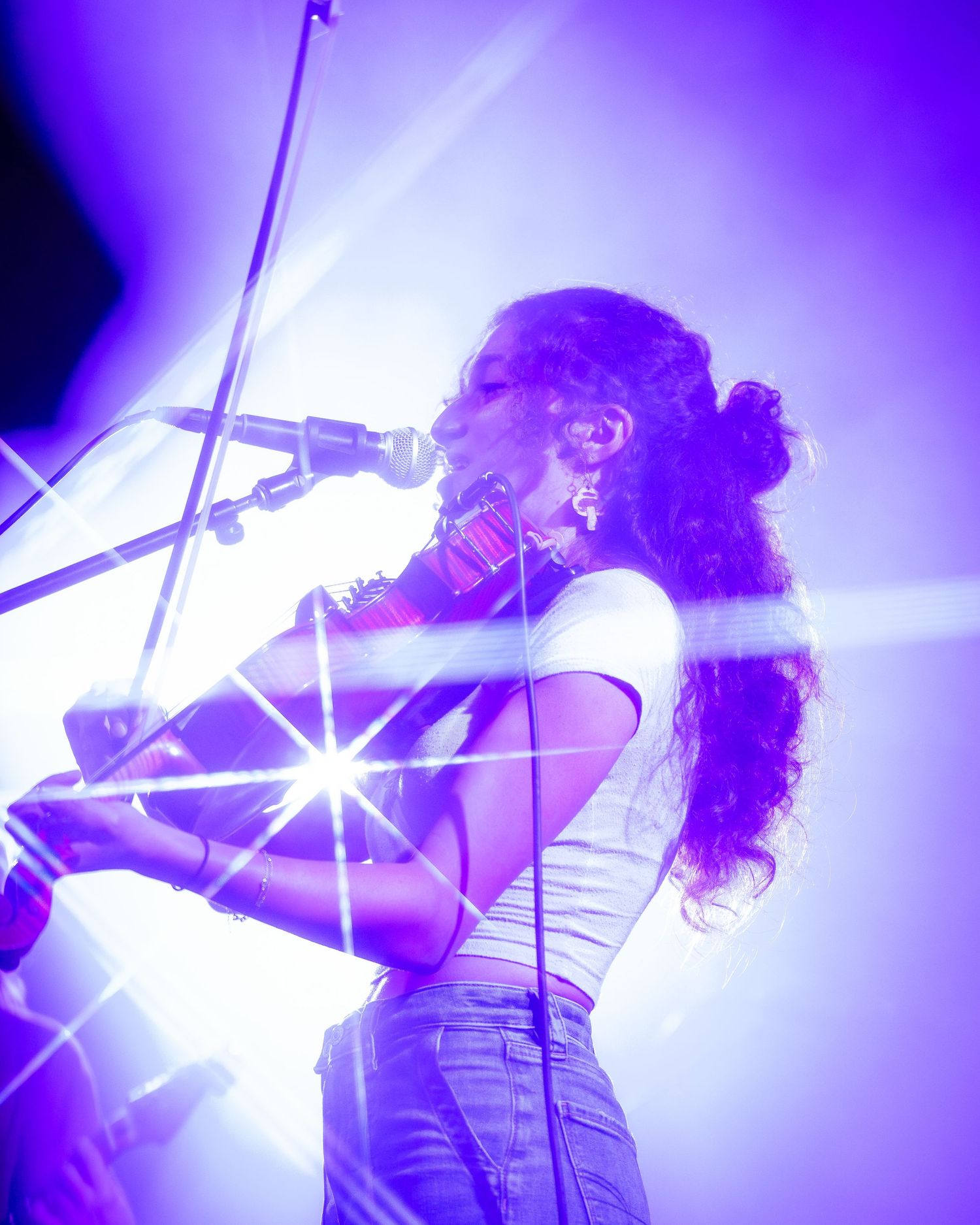 Concert performance bathed in vibrant purple lighting showing dynamic stage movements.