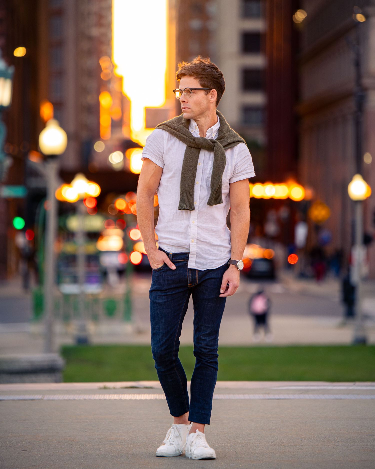 Urban lifestyle photo showing white shirt and dark jeans against evening city lights.