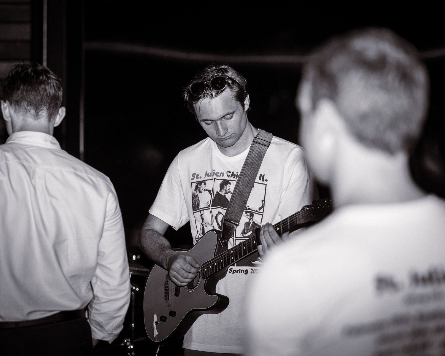 Musician playing electric guitar during performance in black and white.