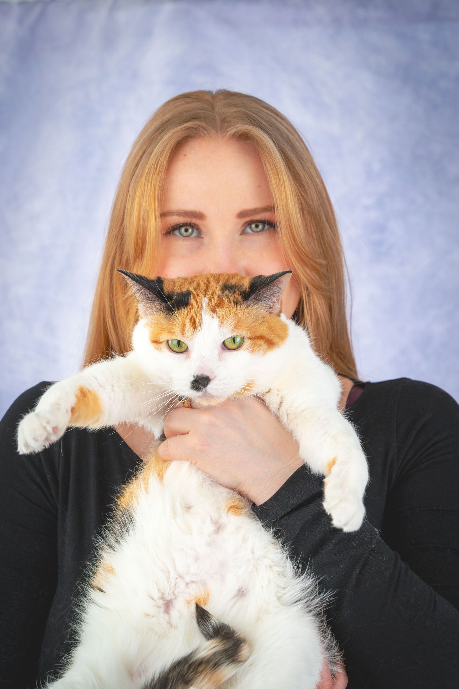 A calico cat is held up playfully in front of someone wearing black in a photo series.