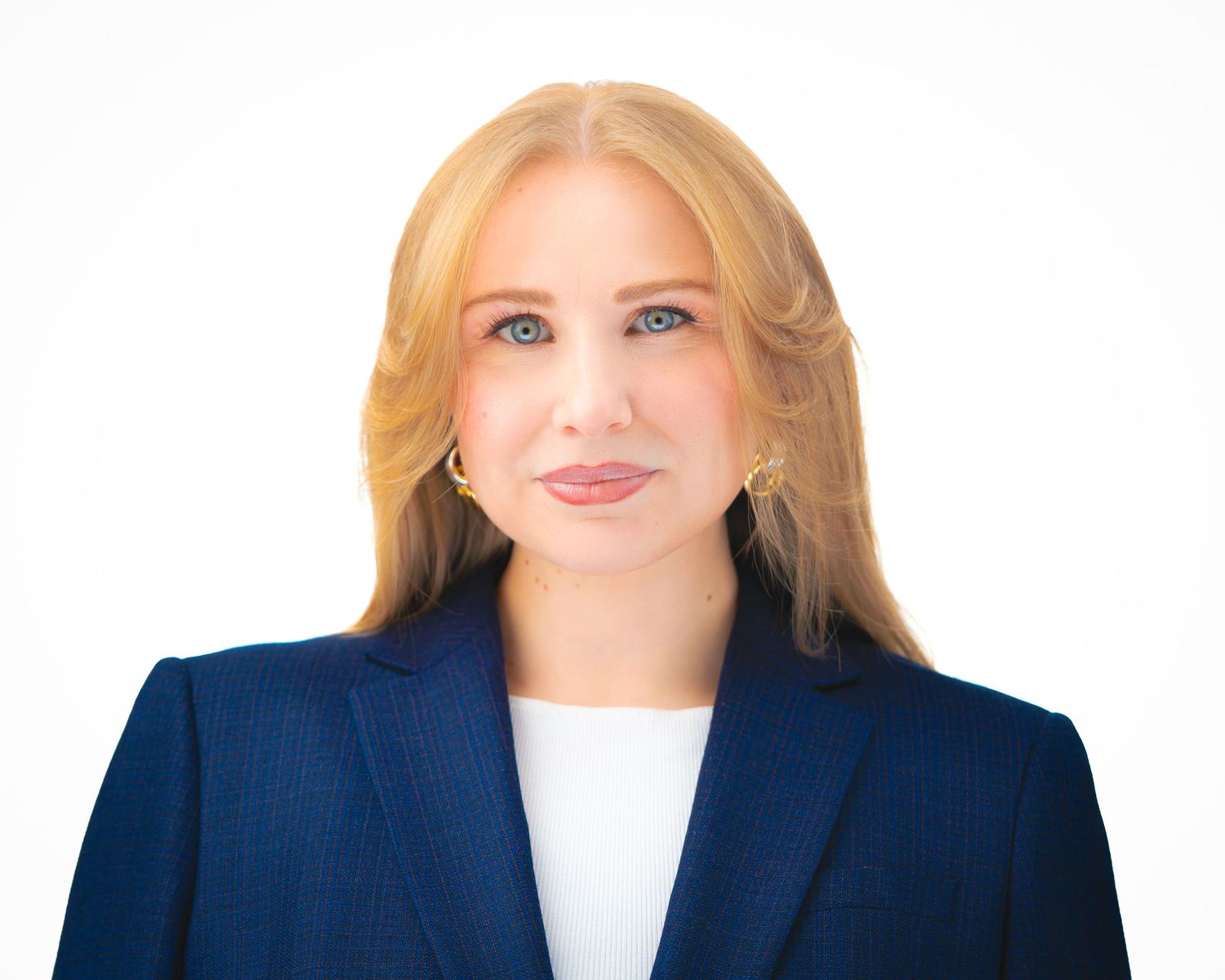 Professional headshot of a person in business attire with blonde hair against a dark background.