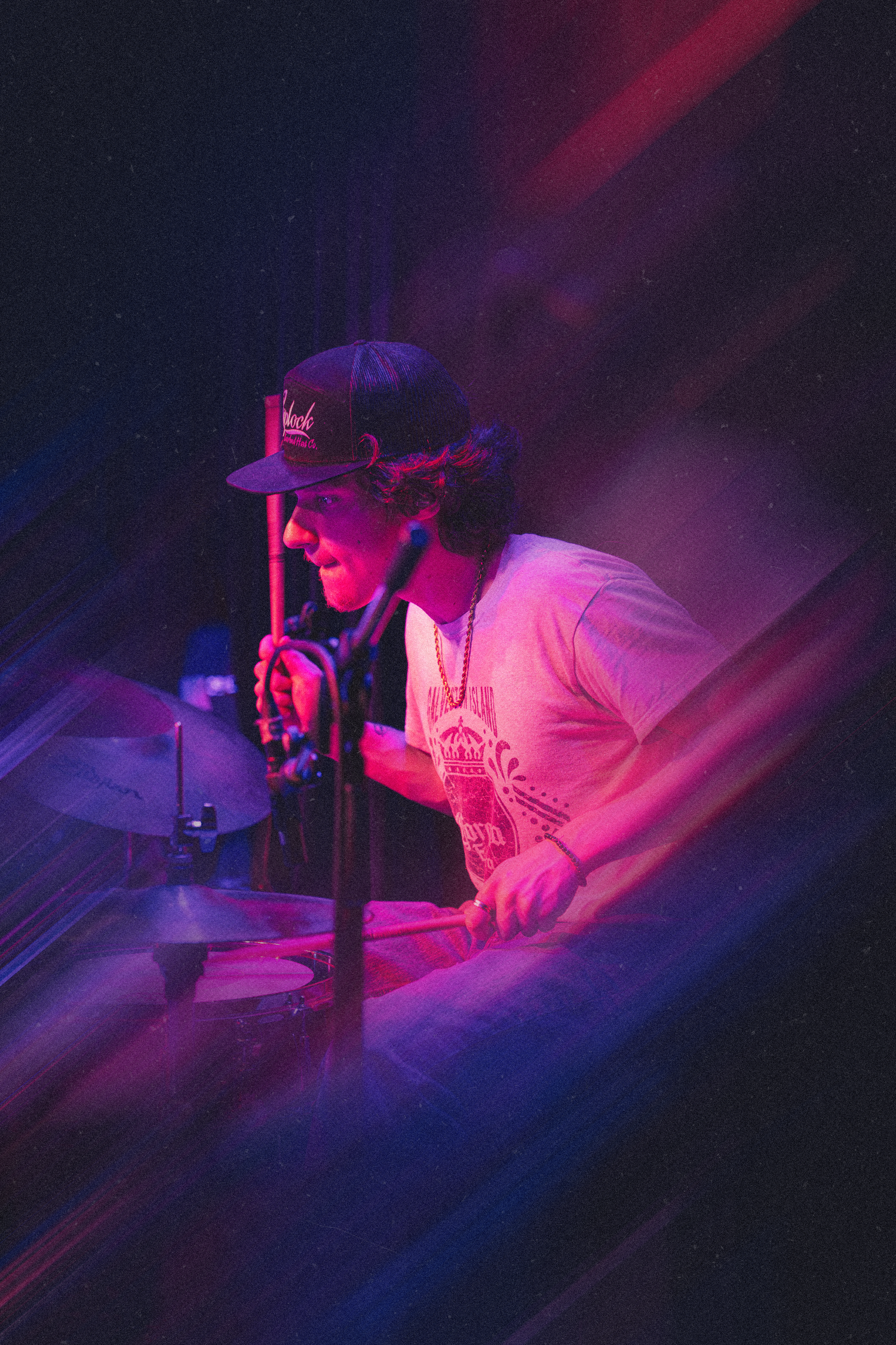 Person performs on stage under dramatic purple and pink lighting creating a moody atmospheric effect.