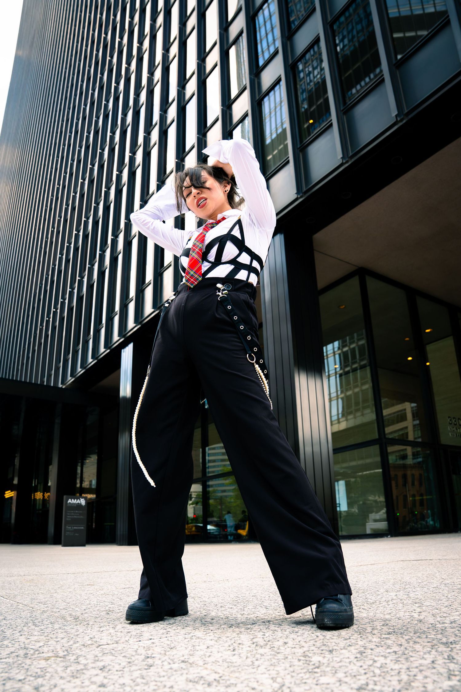 Street fashion photo featuring wide-leg pants and white shirt against modern architecture.
