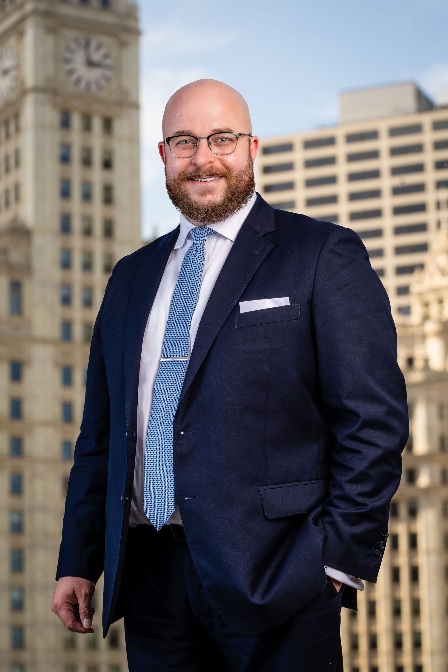 Business professional poses in navy suit against architectural backdrop in downtown setting.