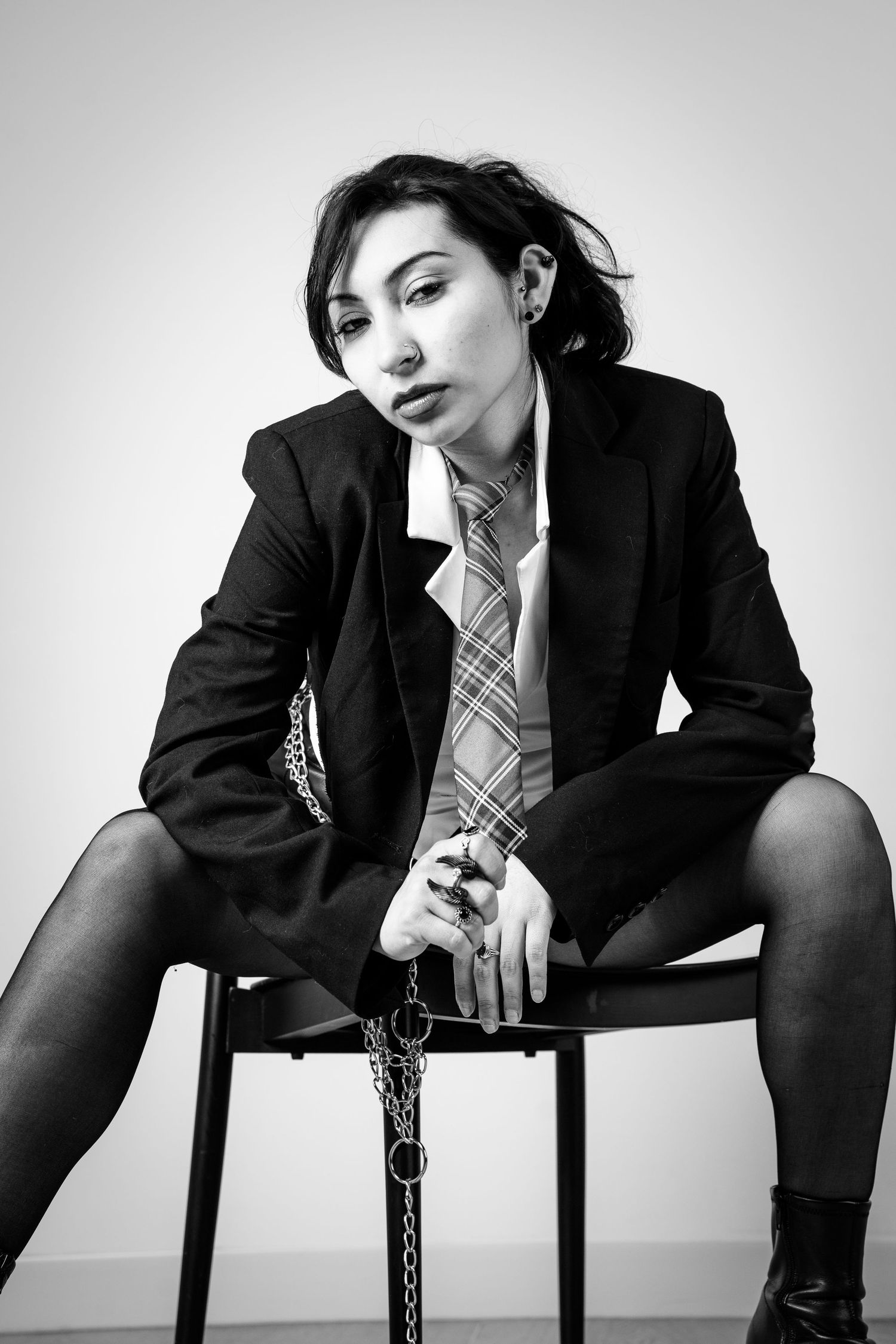 Monochrome fashion series featuring model in business attire posing with chairs.