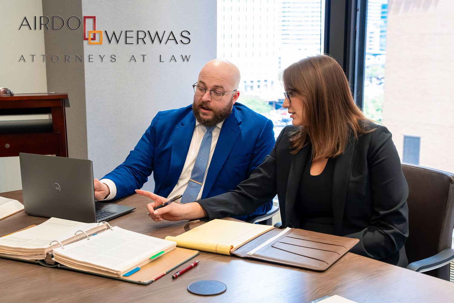 Attorneys discussing case details during meeting at modern law firm.