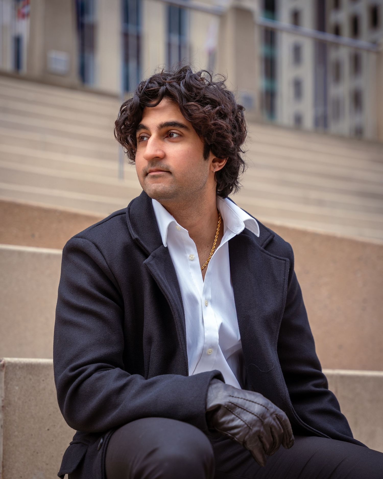 Person in business attire sitting on stone steps in urban setting.