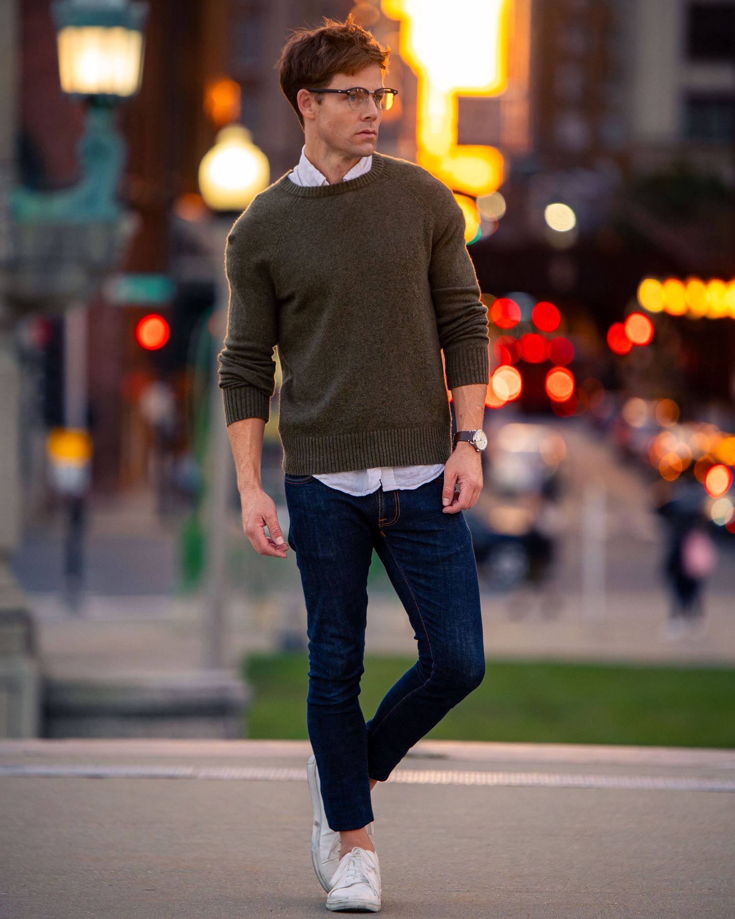Dynamic street fashion photography with olive sweater and jeans in urban setting.