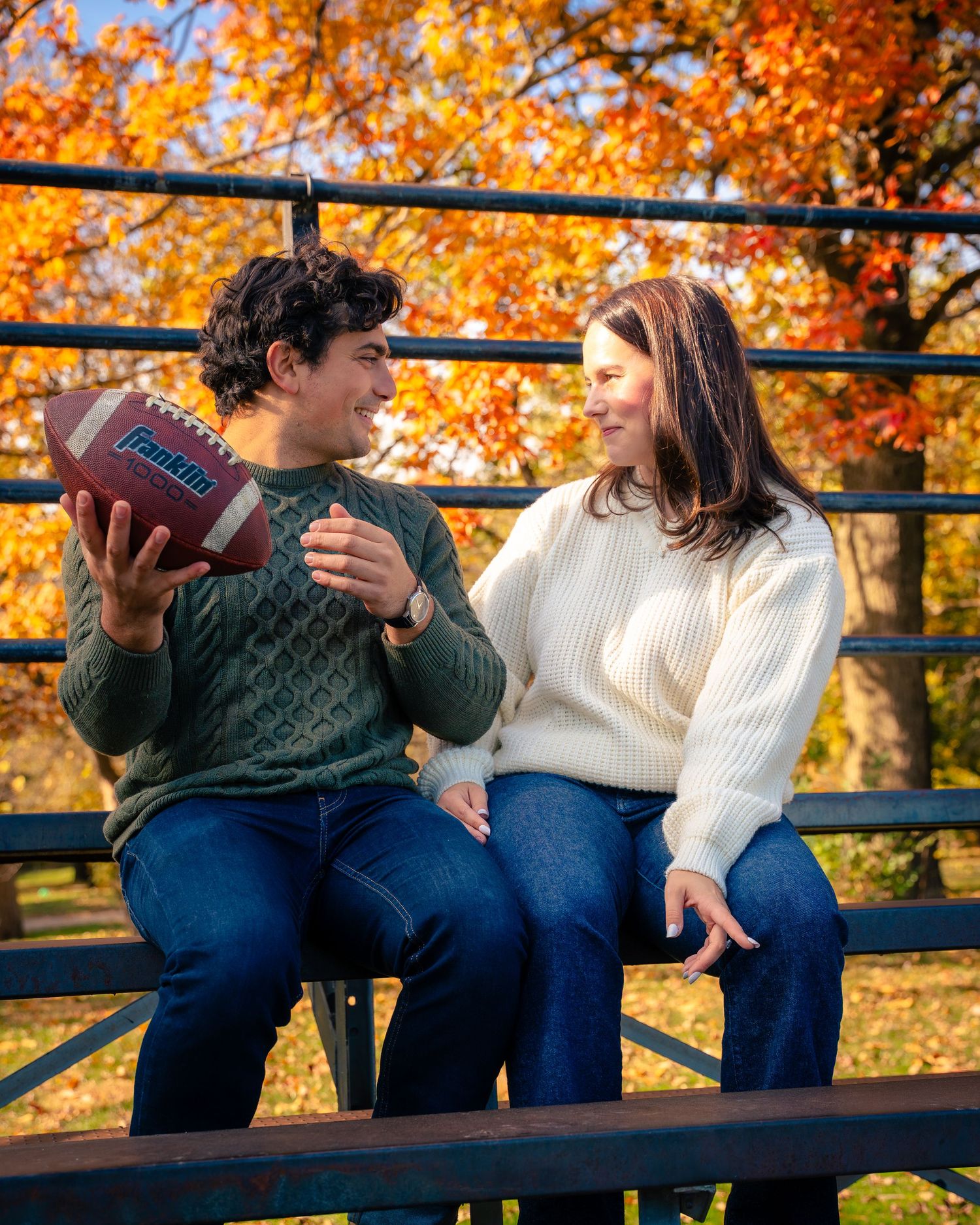 Two people relaxing on a bench with beautiful fall colors in the background.