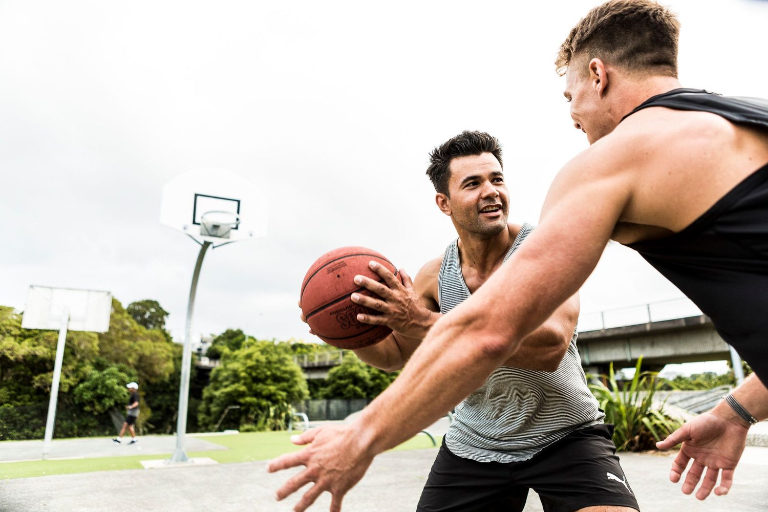 Two athletes engage in a competitive game of basketball on an outdoor court.