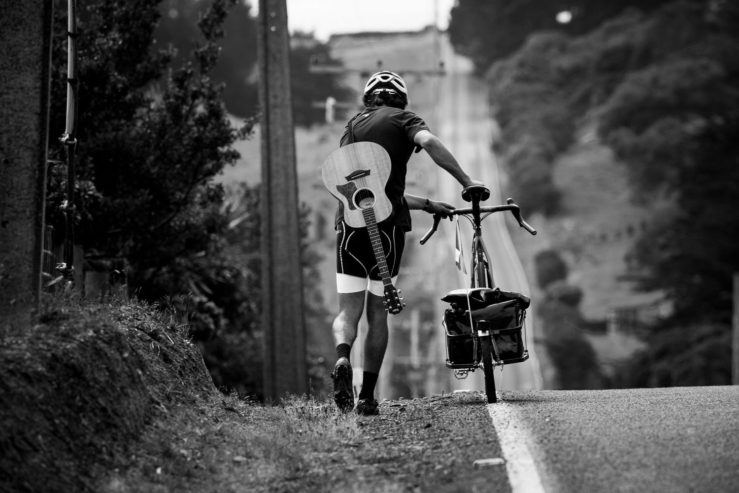 Black and white photo of cyclist celebrating on rural road with arms raised triumphantly.