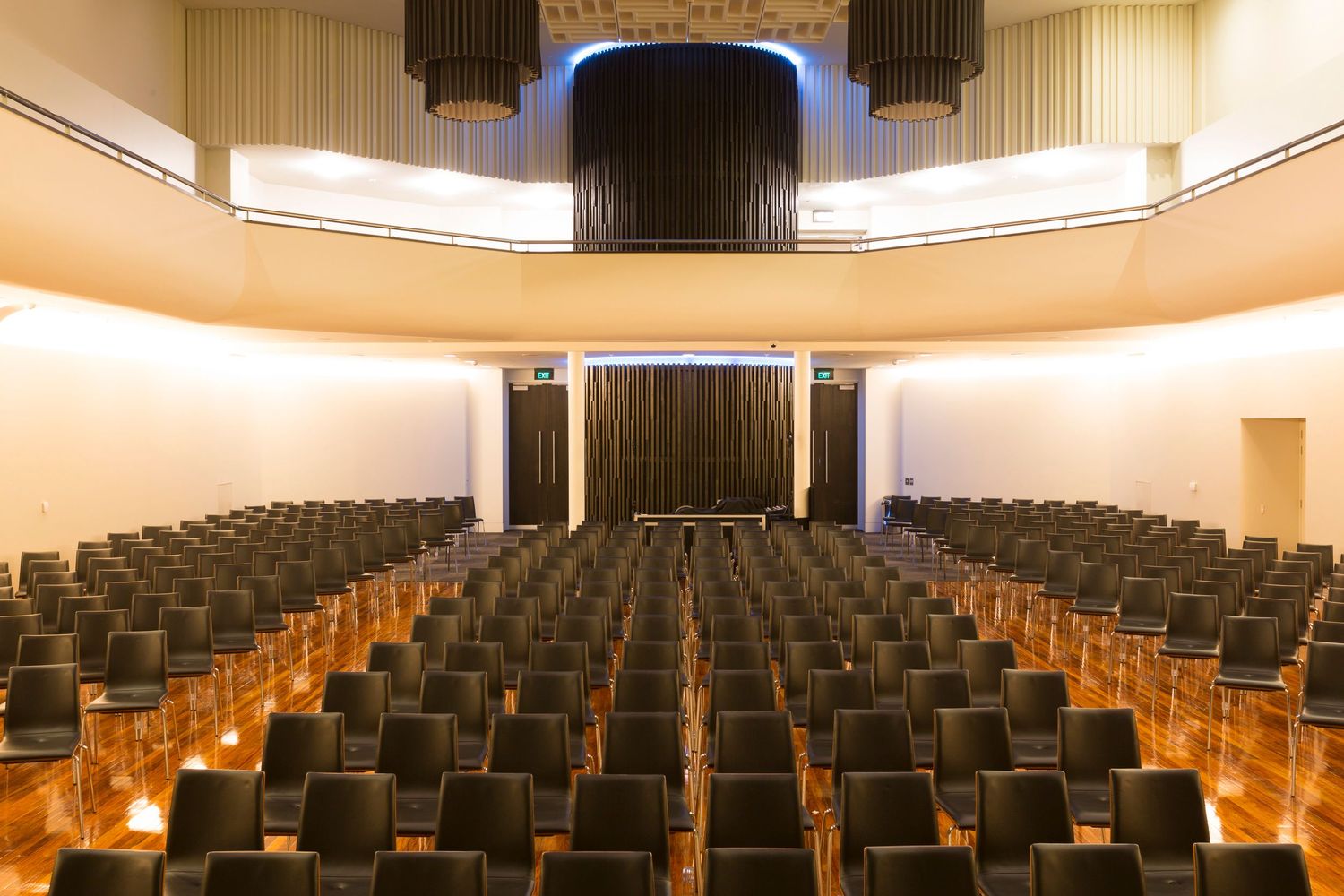 Modern auditorium with rows of stadium seating and a stage illuminated by warm lighting.