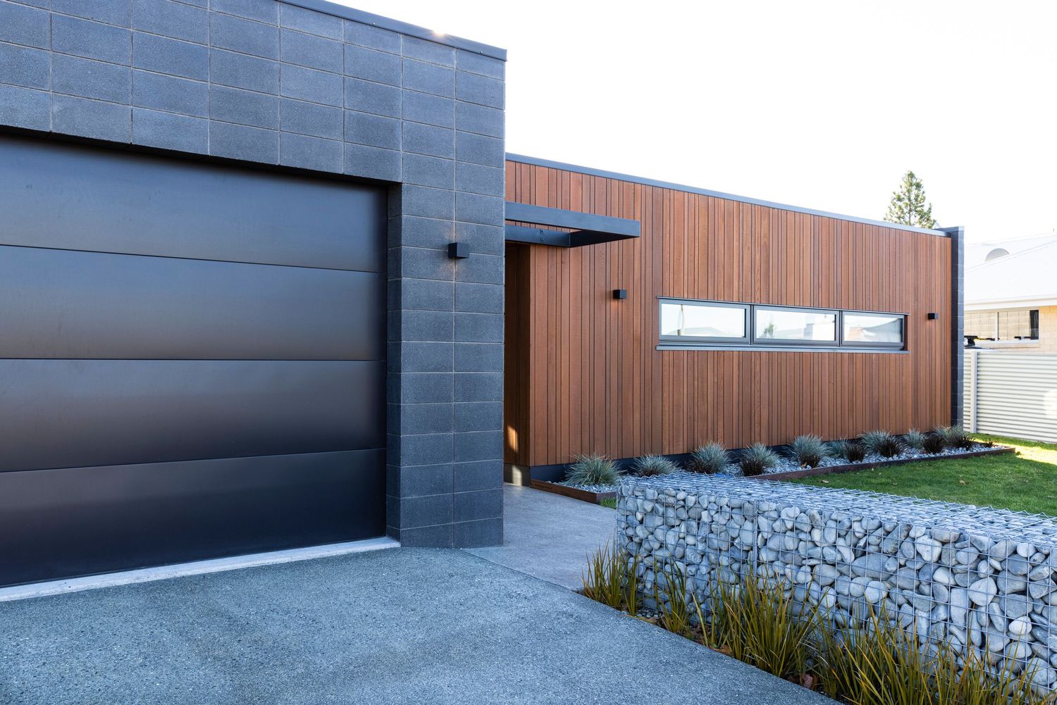 Contemporary dark gray and wood exterior with minimalist landscaping details.