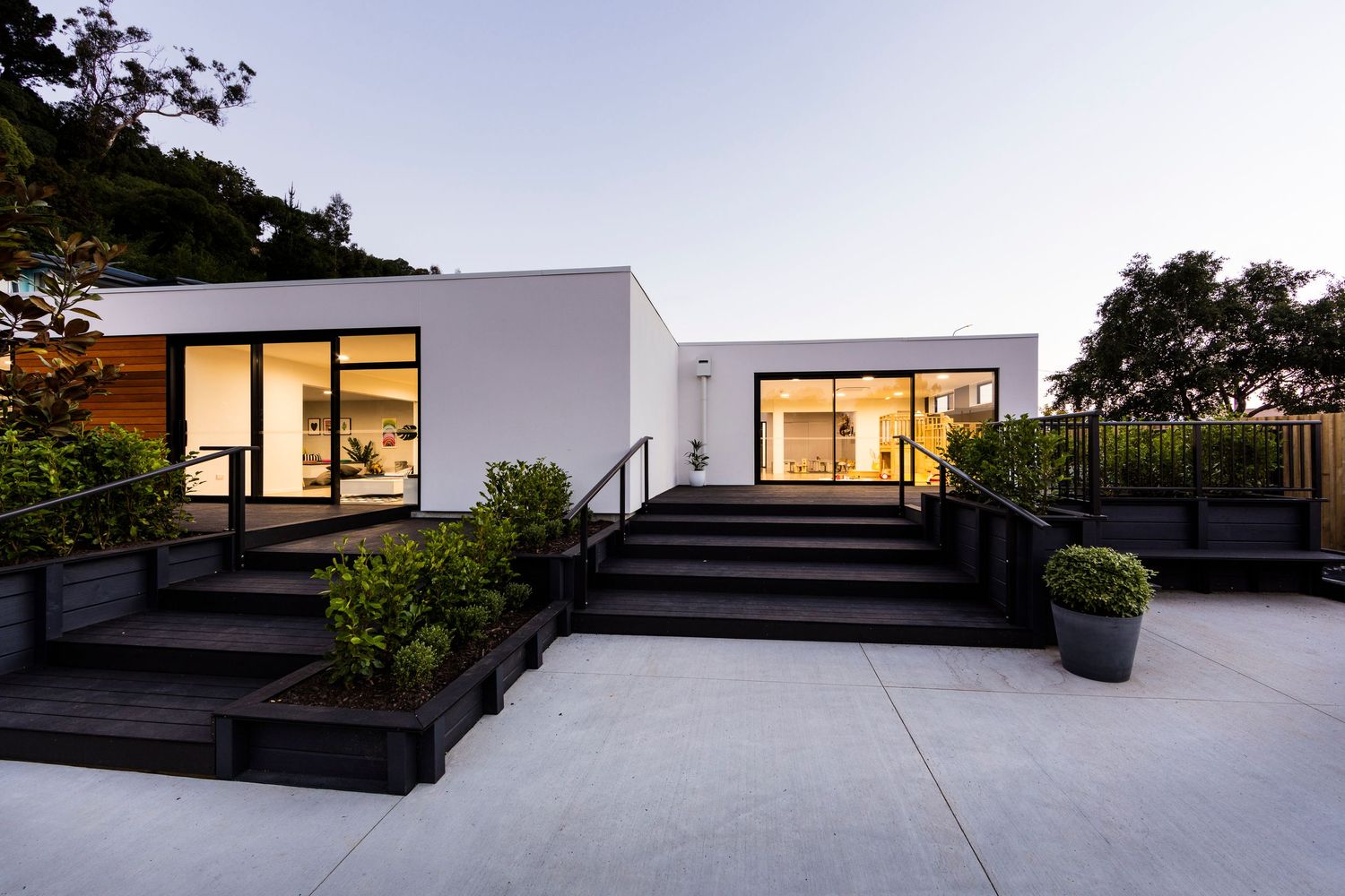 Modern luxury home exterior with clean lines, glass walls, and outdoor lighting at dusk.