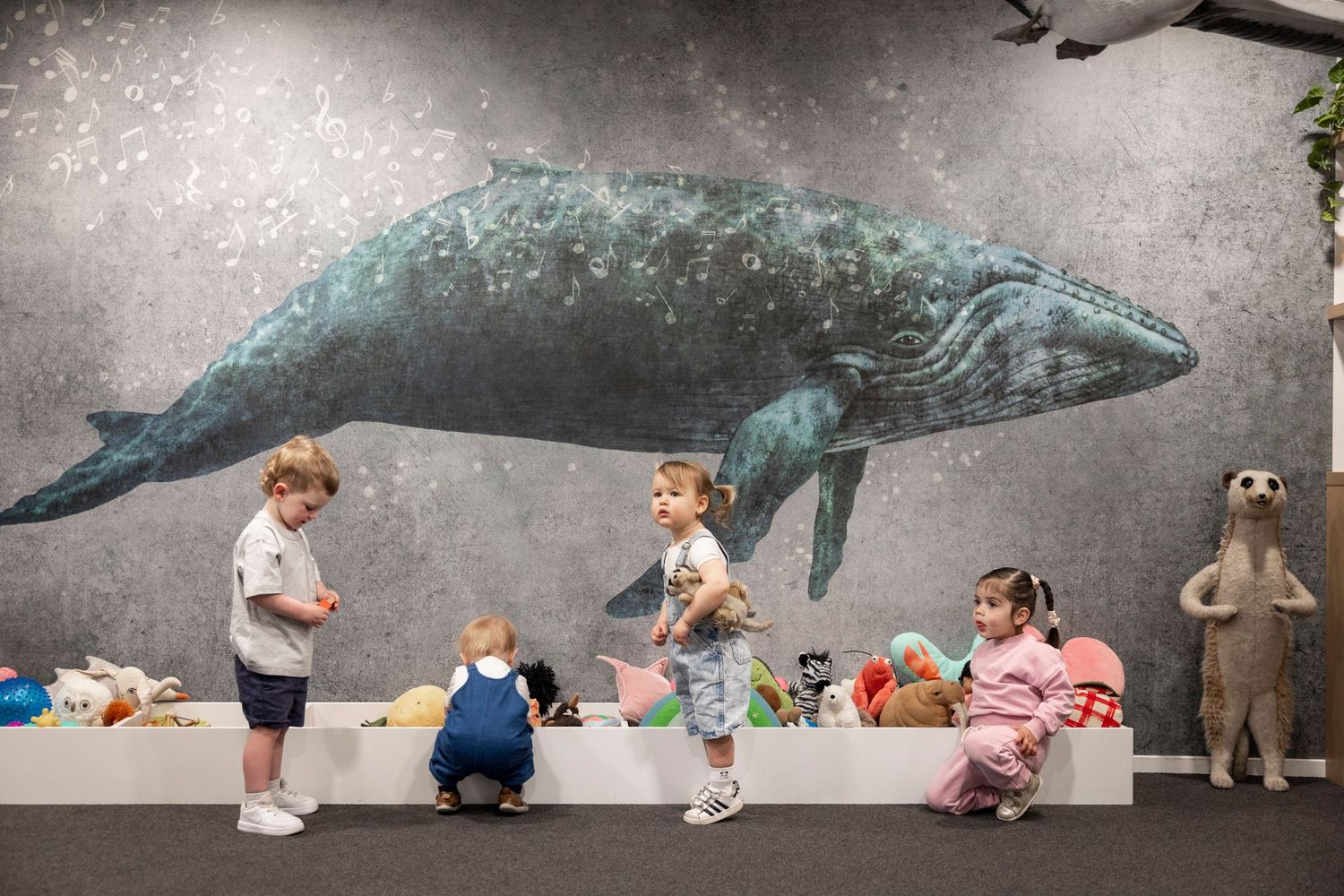 Children interacting with large whale mural in educational space.