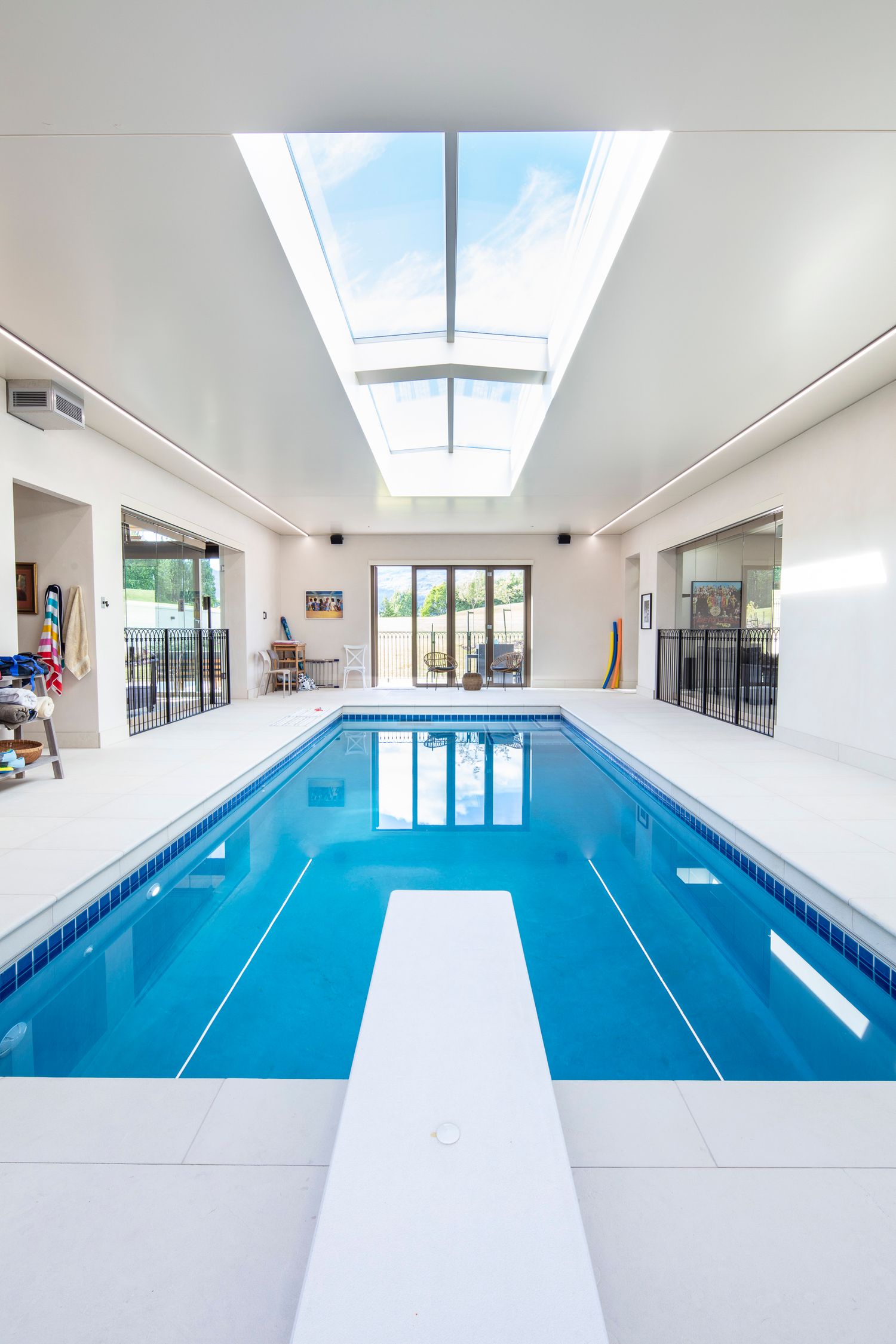 Indoor lap pool with skylights illuminating a bright white interior and blue swimming lanes.
