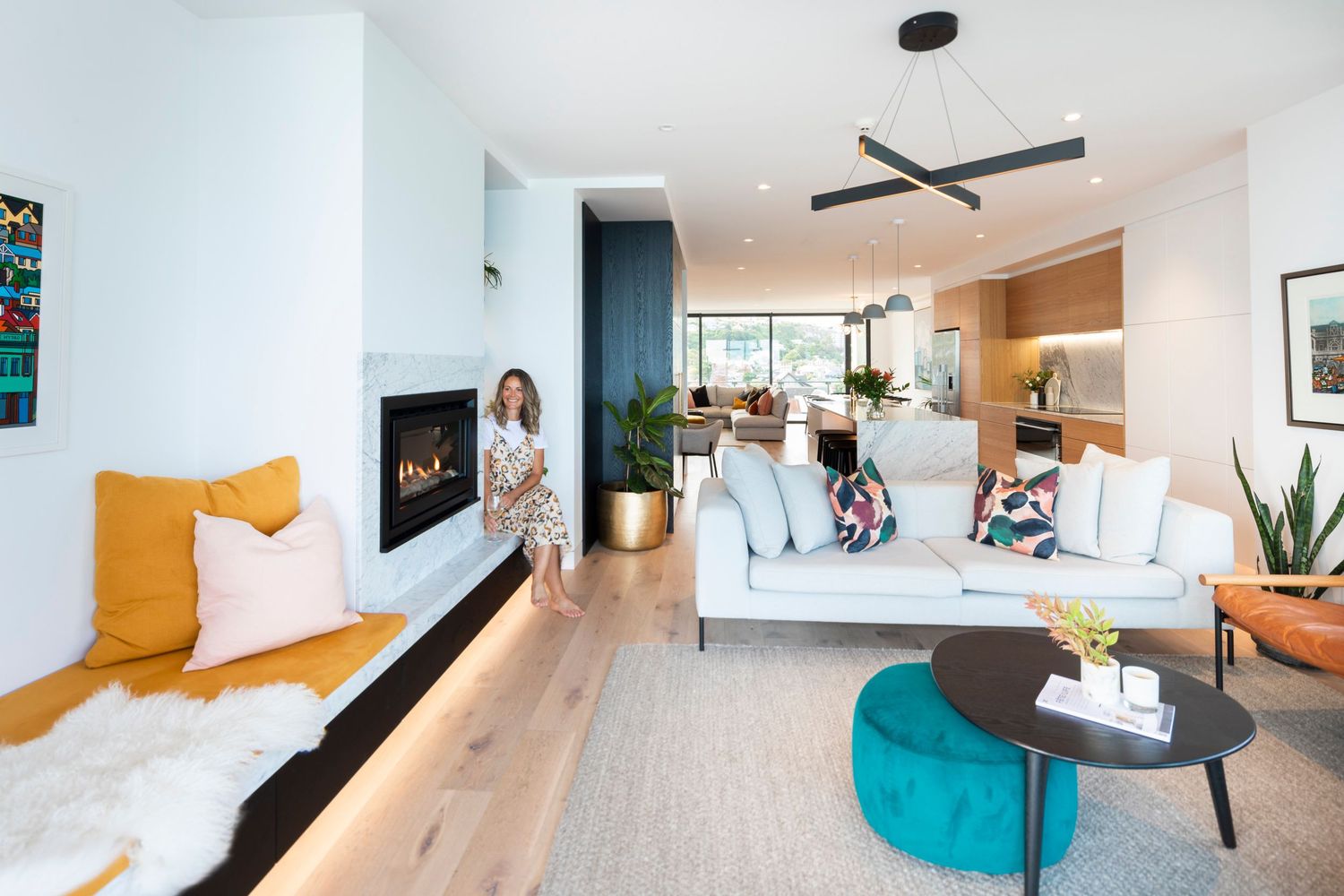 Contemporary living space with gas fireplace and teal ottoman centerpiece.